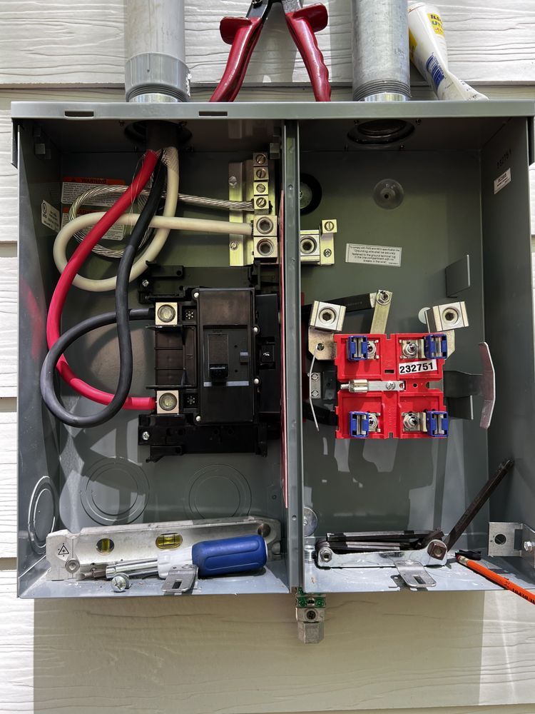 Open electrical breaker box with red and black wiring exposed