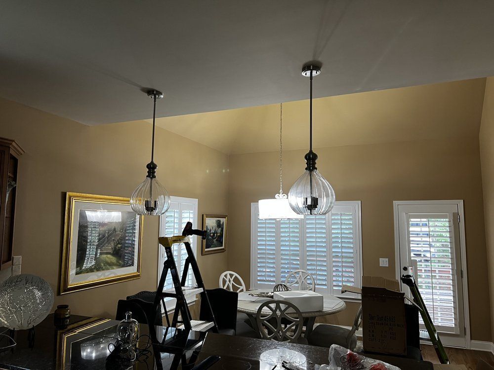 Dining room with beige walls, pendant lights, large window, and exercise equipment inside