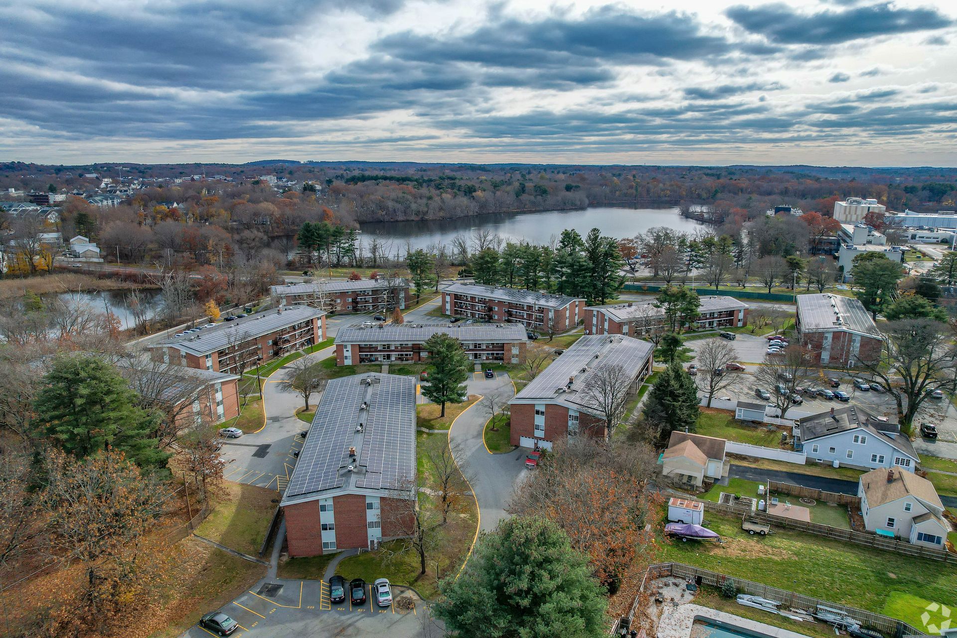 Aerial view of apartment buildings near a lake, under a cloudy sky.