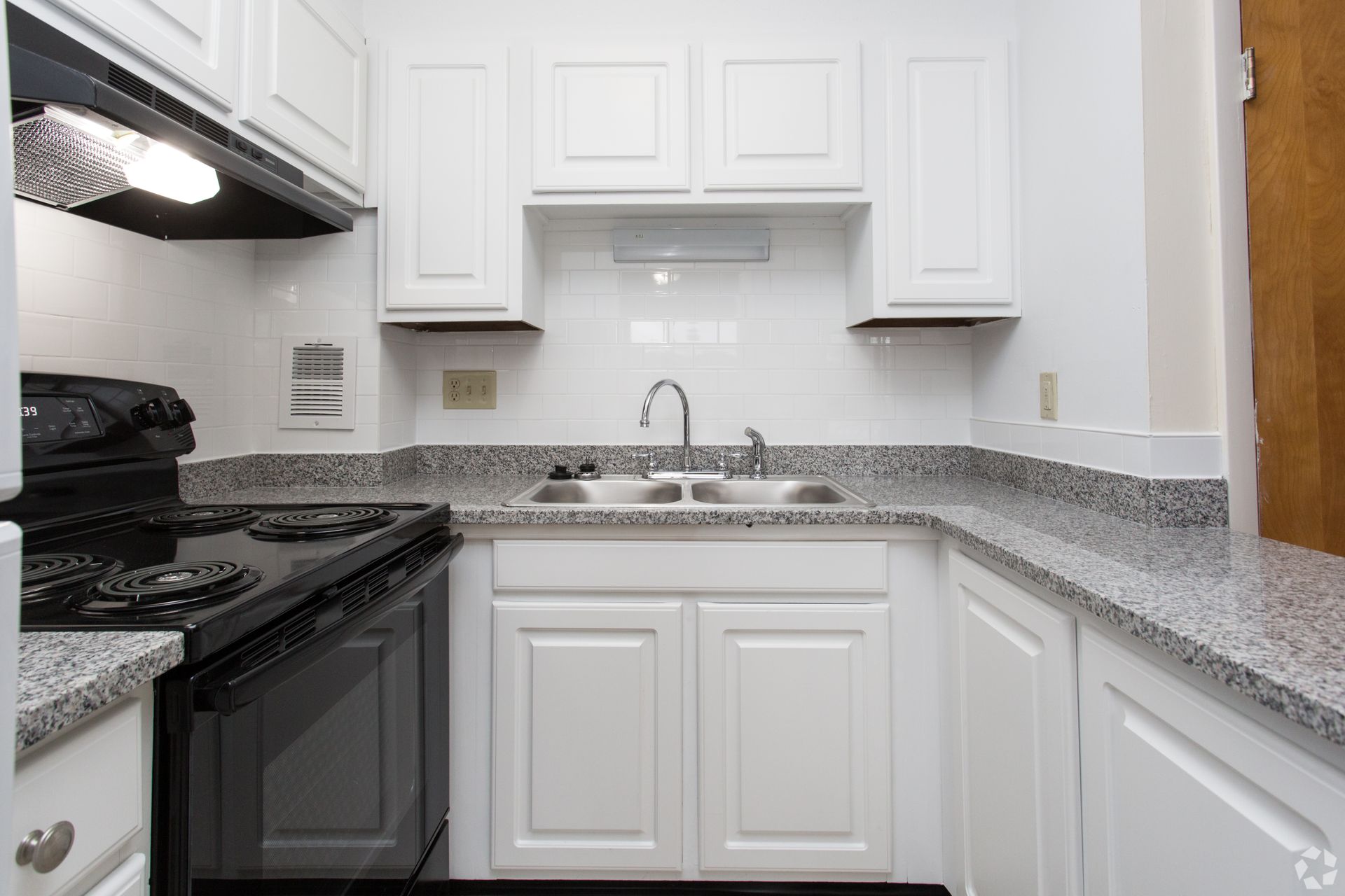 White kitchen with black appliances, gray countertops, and white cabinets.