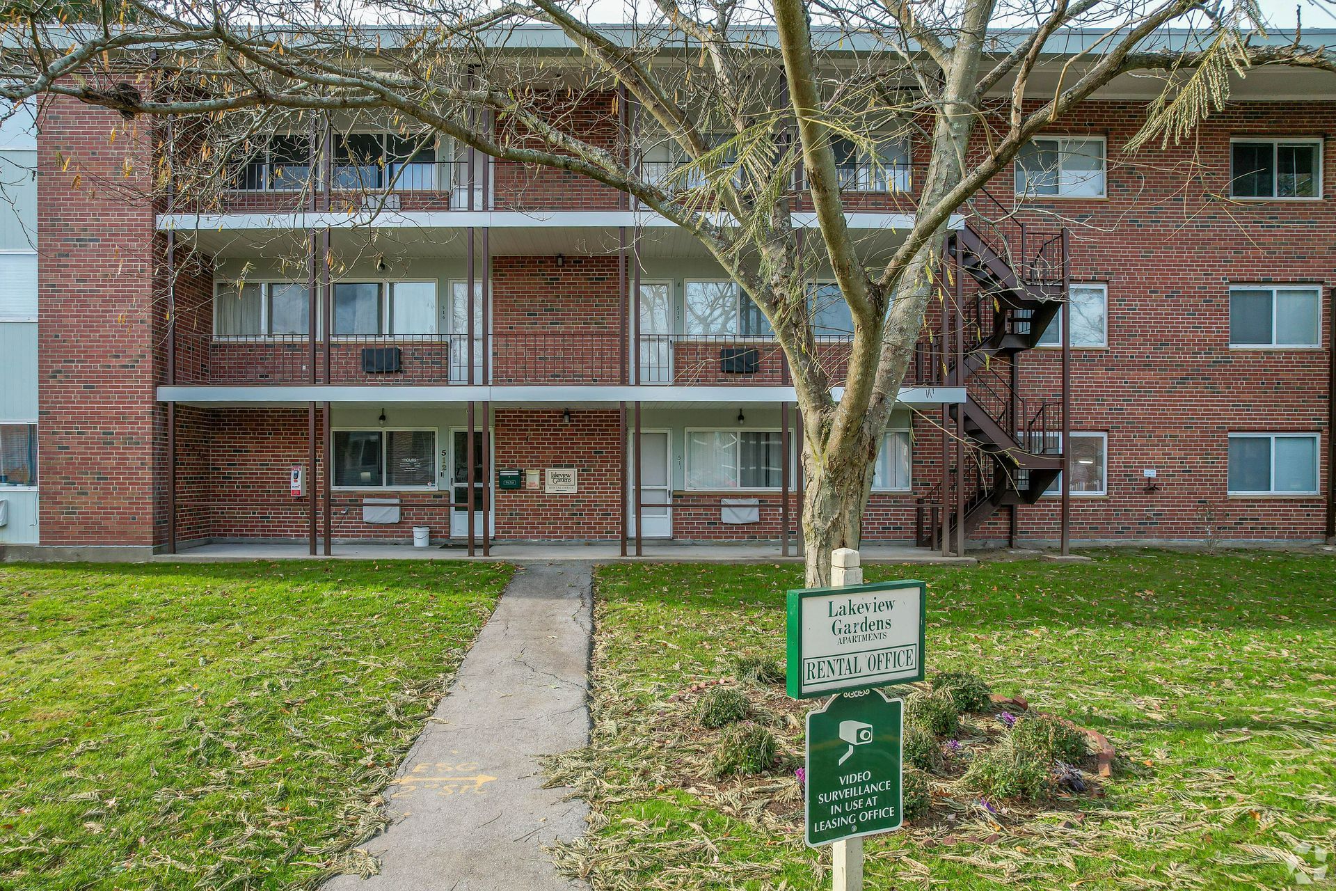 Brick apartment building with green lawn and sign.