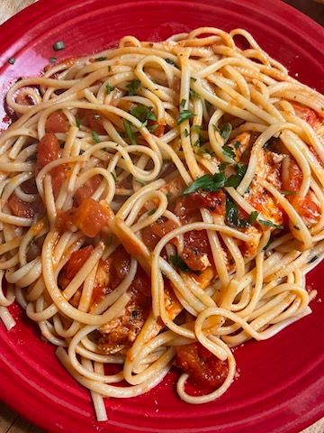 A red plate topped with spaghetti and tomato sauce.