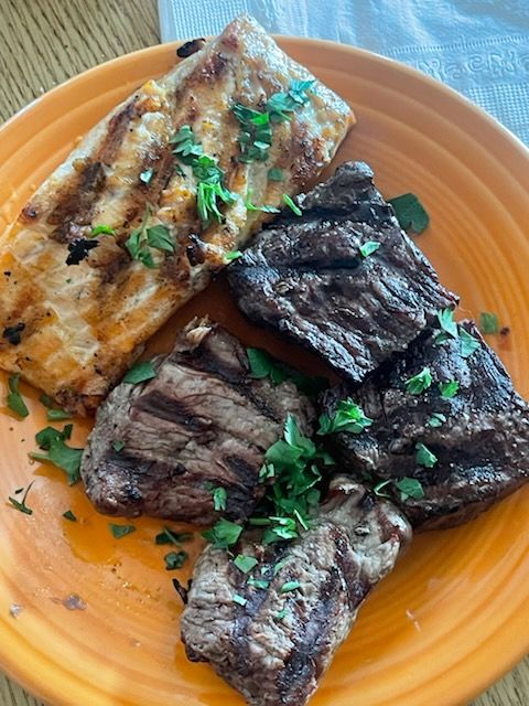 A close up of a plate of meat and fish on a table