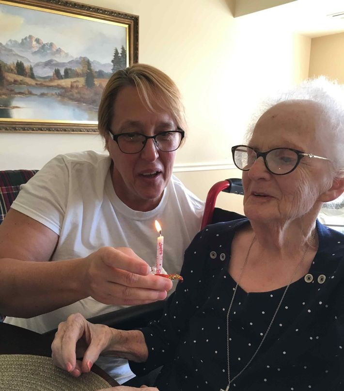 Woman holding a candle for an elderly woman | Joliet, IL | Friends over Fifty Senior Care