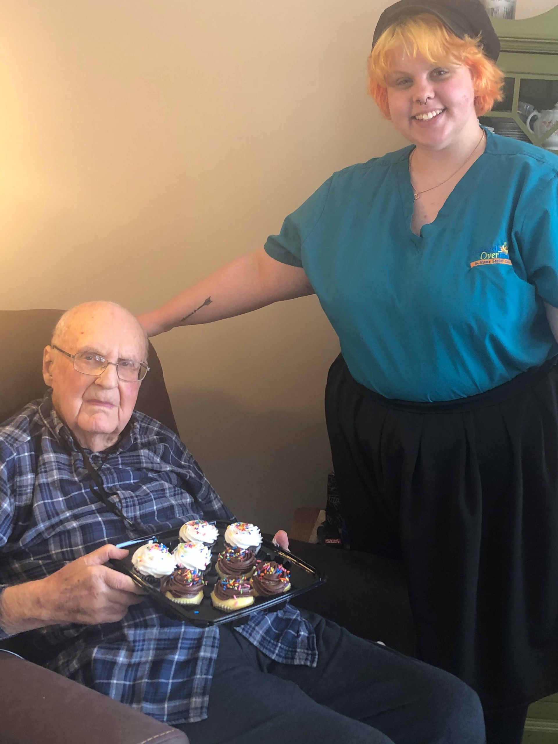 Senior man holding tray of cupcakes and a lady | Joliet, IL | Friends over Fifty Senior Care