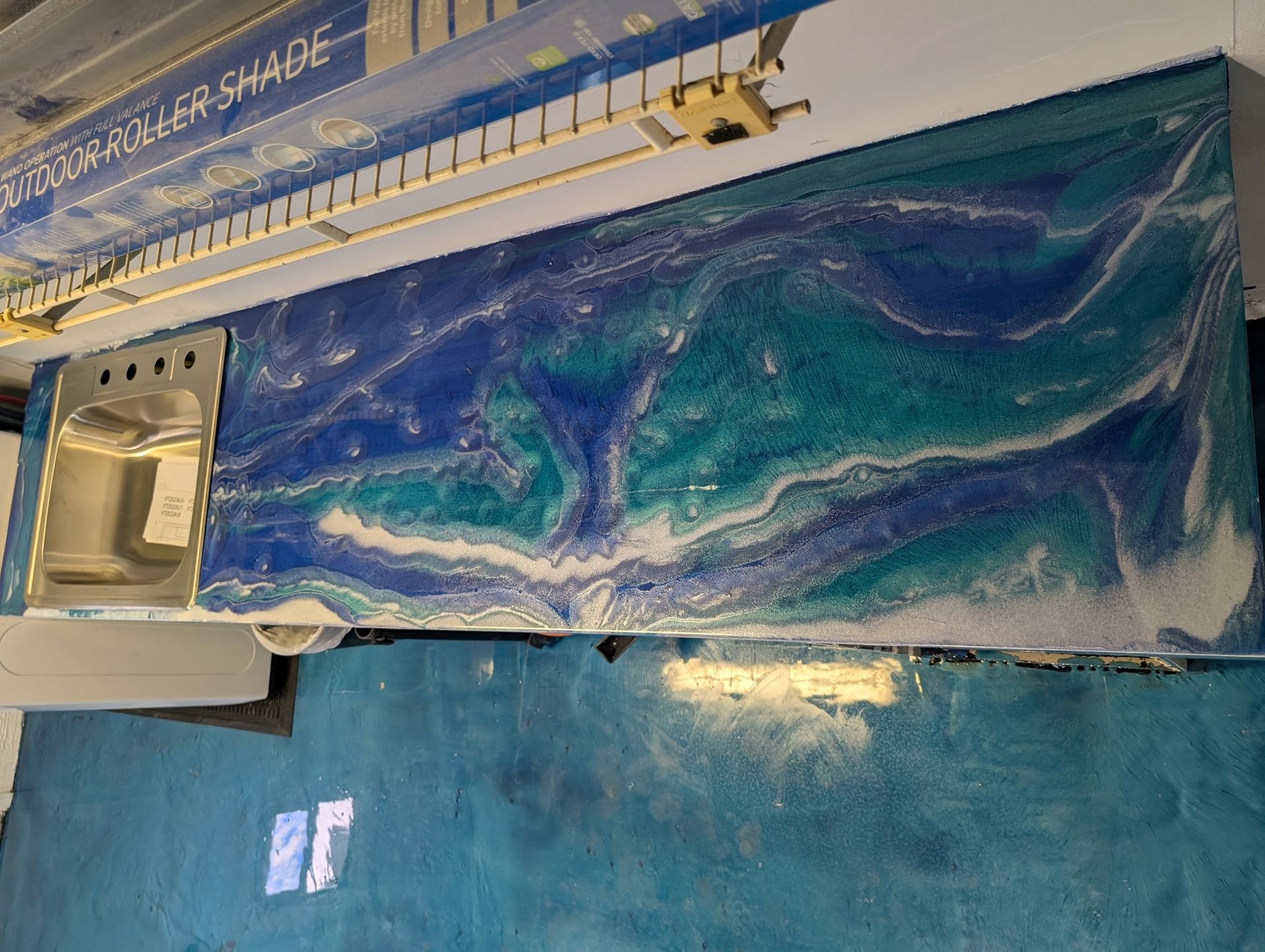 Blue and teal epoxy countertop with sink, swirling patterns.