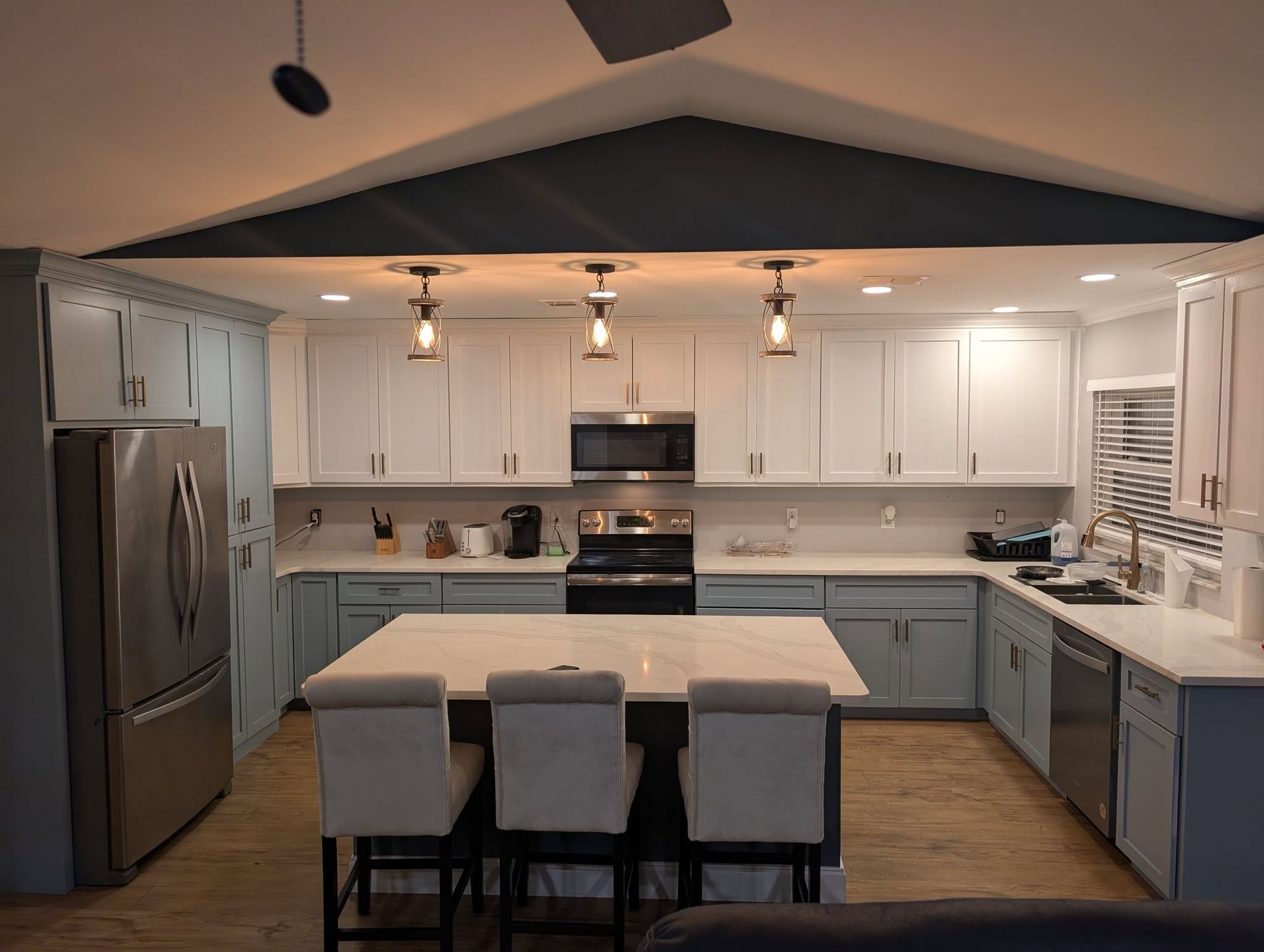 Modern kitchen with blue and white cabinets, a large island, and pendant lights.