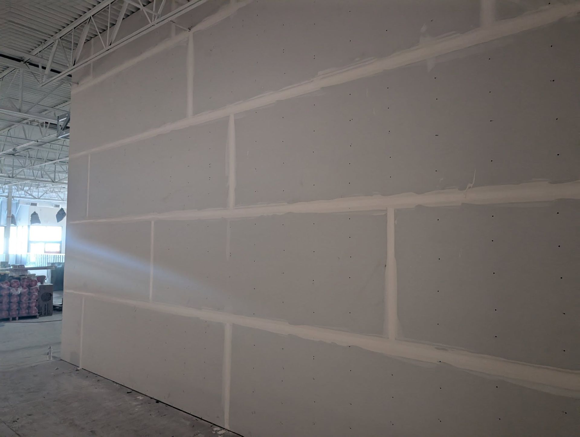Drywall wall under construction; light gray boards with white joint compound.