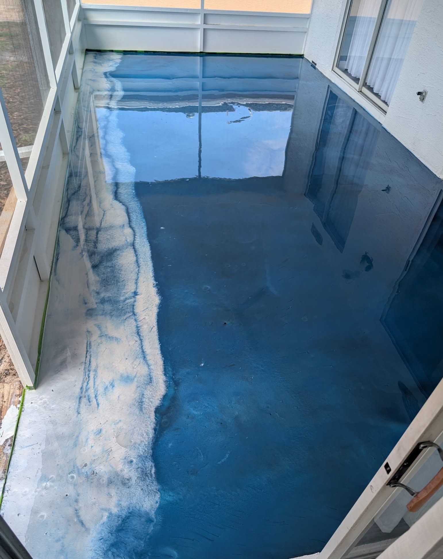 Blue epoxy floor with light blue and white accents reflecting the sky in a sunroom.