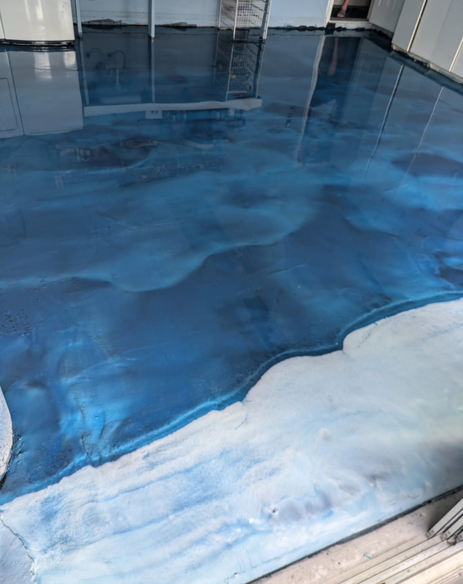 Blue and white epoxy floor with ocean wave design in an indoor setting.