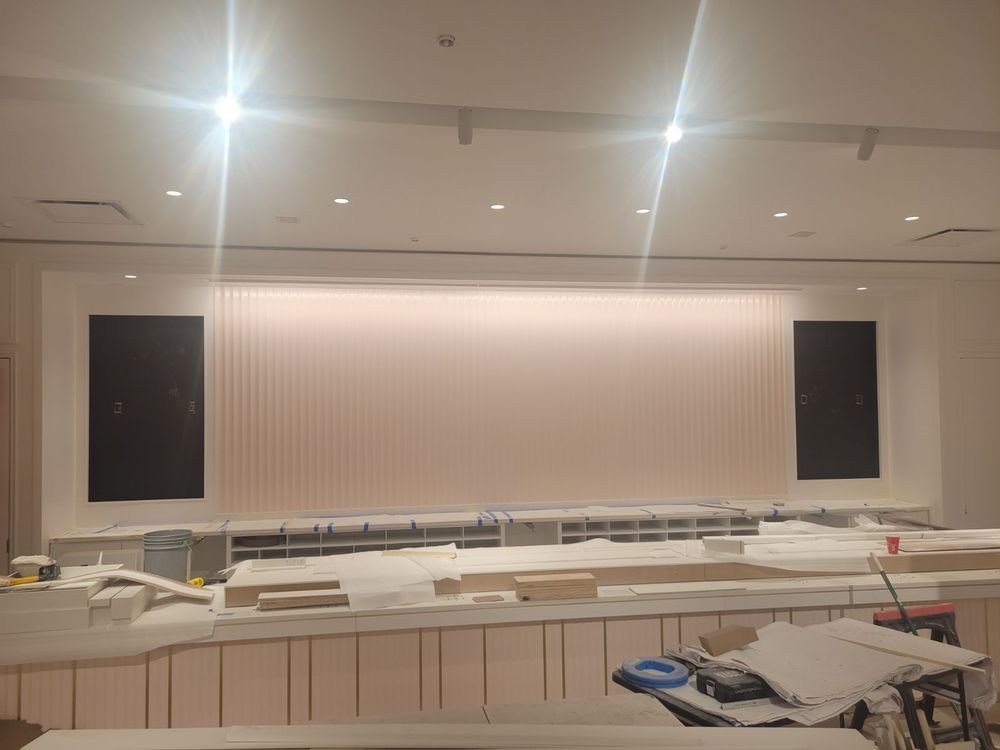 Construction in progress: Pink-toned wall with black screens on either side. Work materials and lights visible.