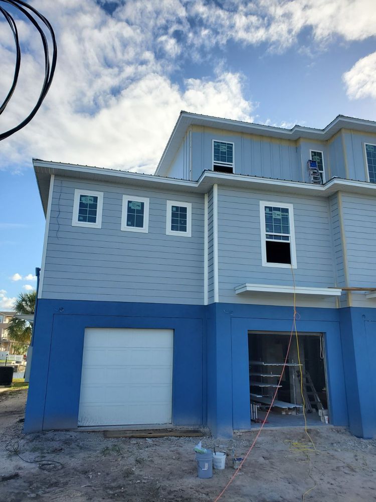 A partially built blue and gray building with garage doors and windows.