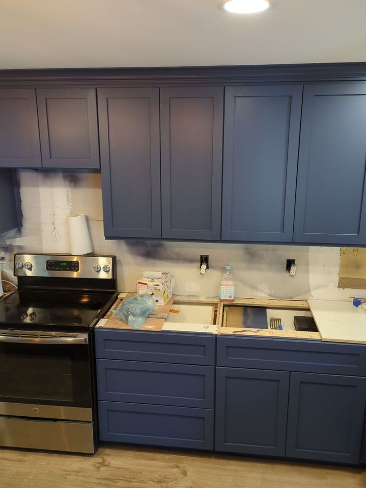 Kitchen with blue cabinets, stove, and exposed wall, undergoing renovation.