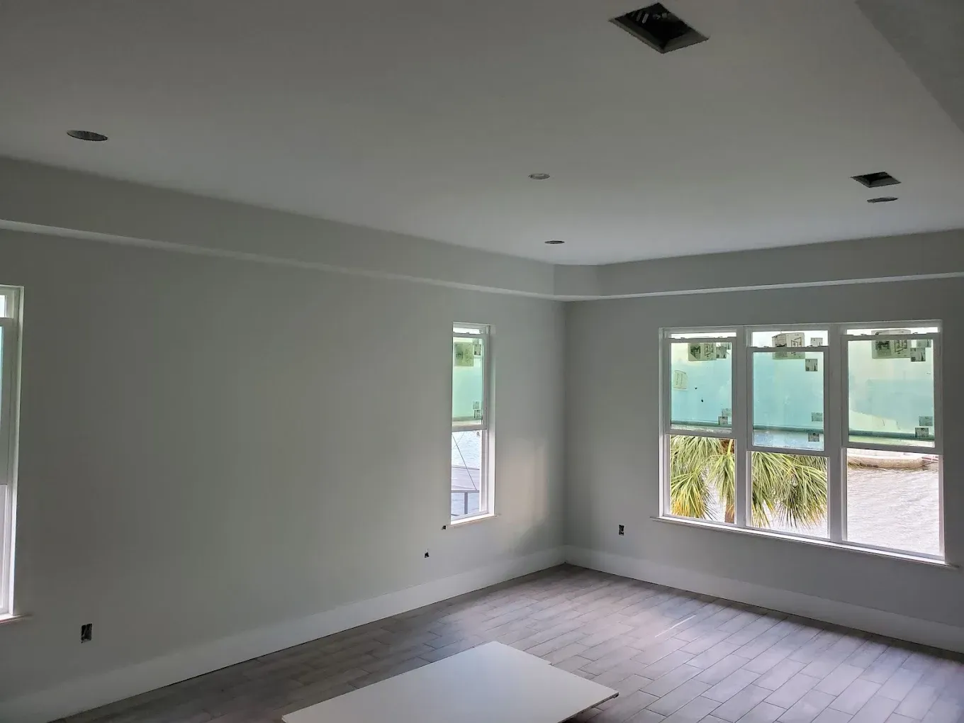 Empty room with gray walls, white trim, recessed lighting, and windows.