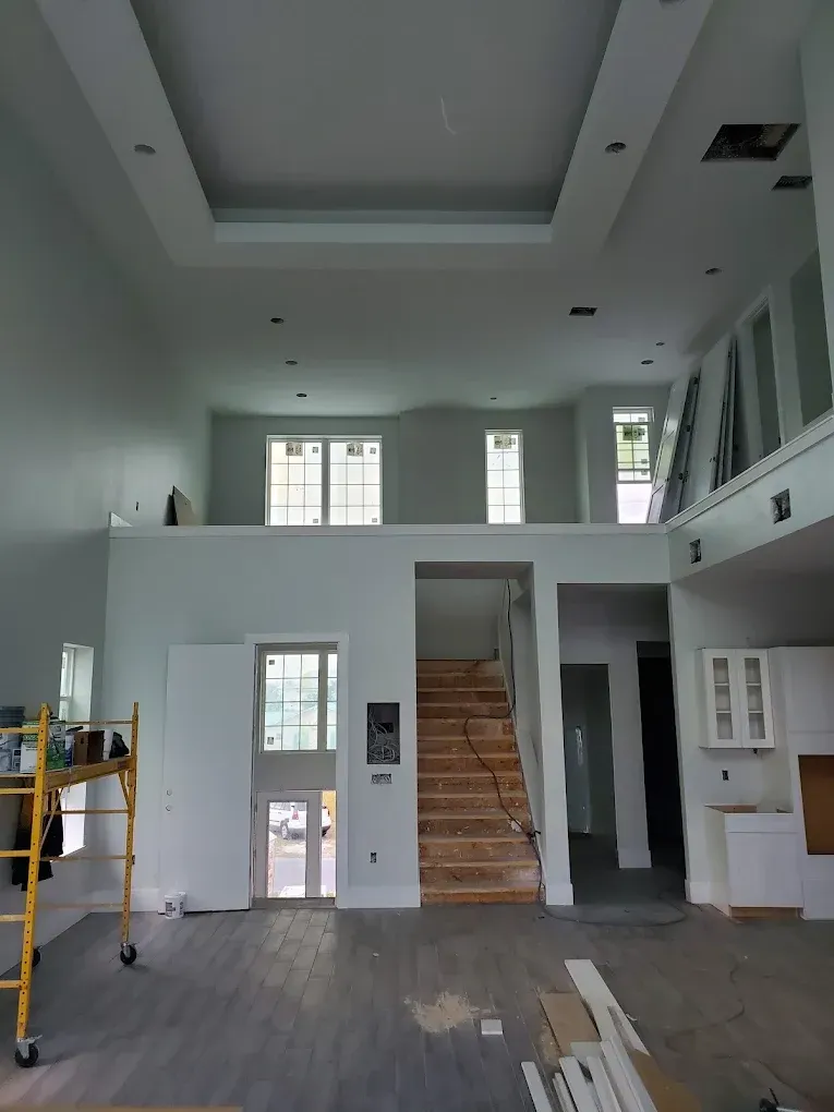 Interior of a home under construction with high ceilings, a staircase, and a second-floor loft area.