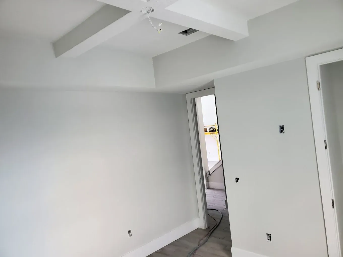 A newly painted, empty room with gray walls, white trim, and a doorway.