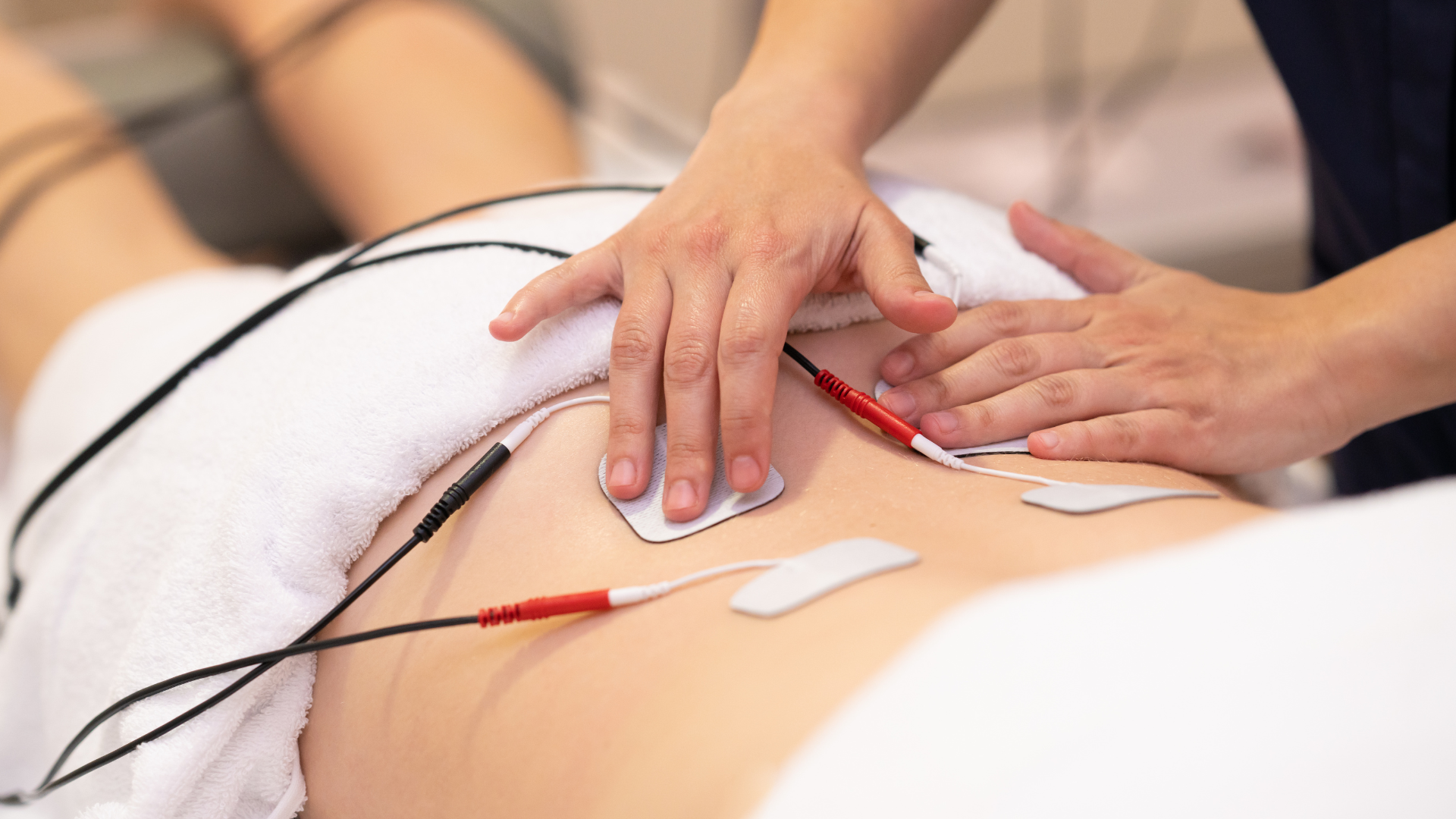 A person is getting a massage with electrodes on their back.