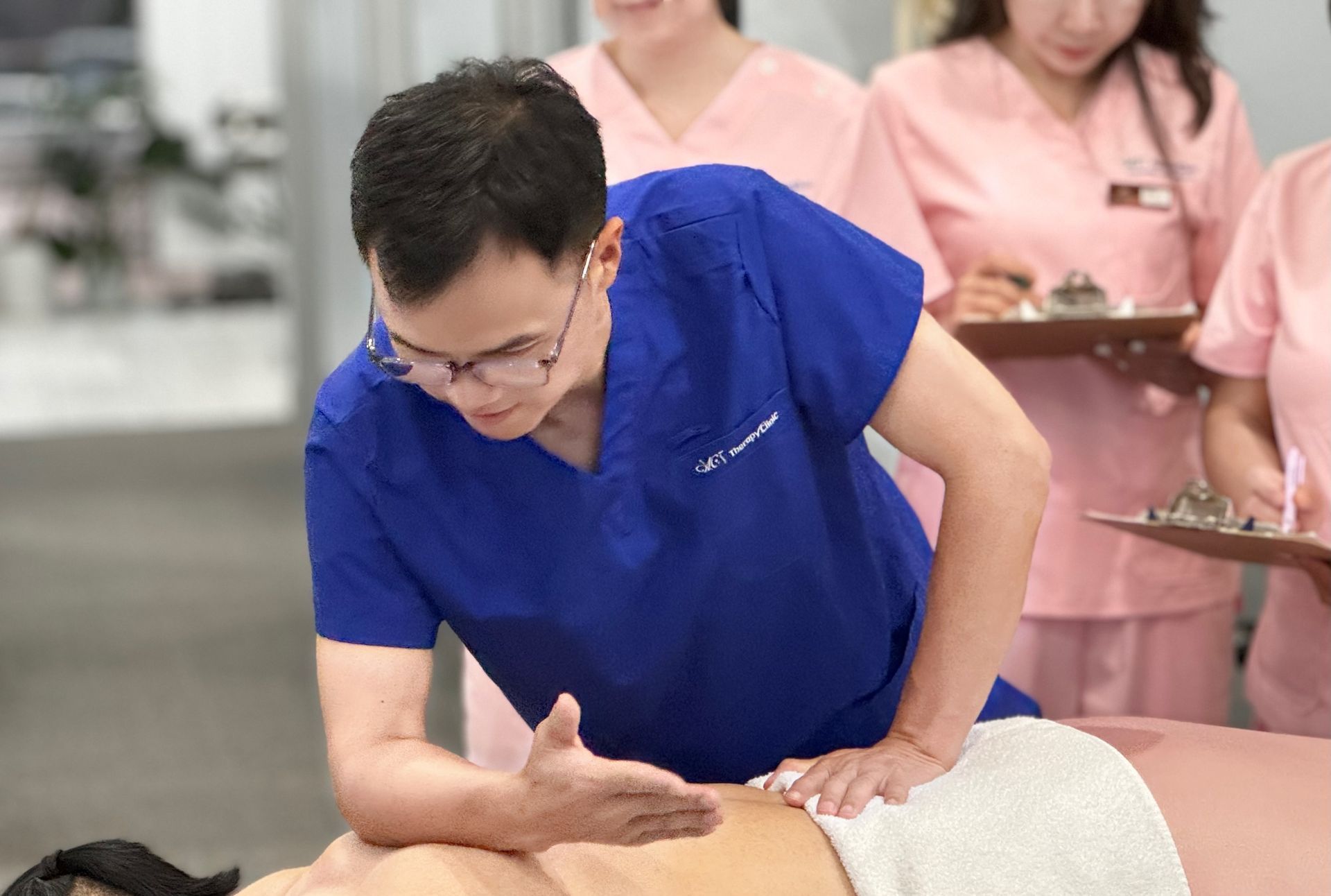 A man in a blue scrub is giving a massage to a woman.
