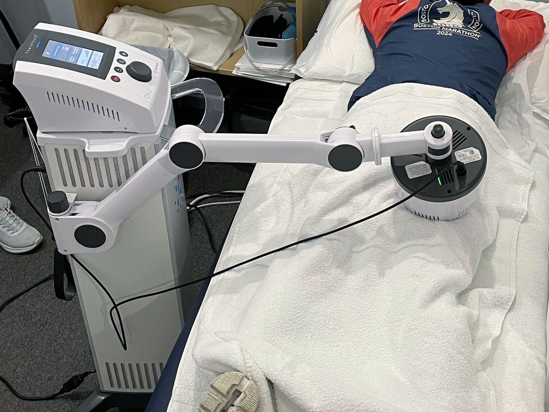 A person is laying on a bed with a machine on their back.
