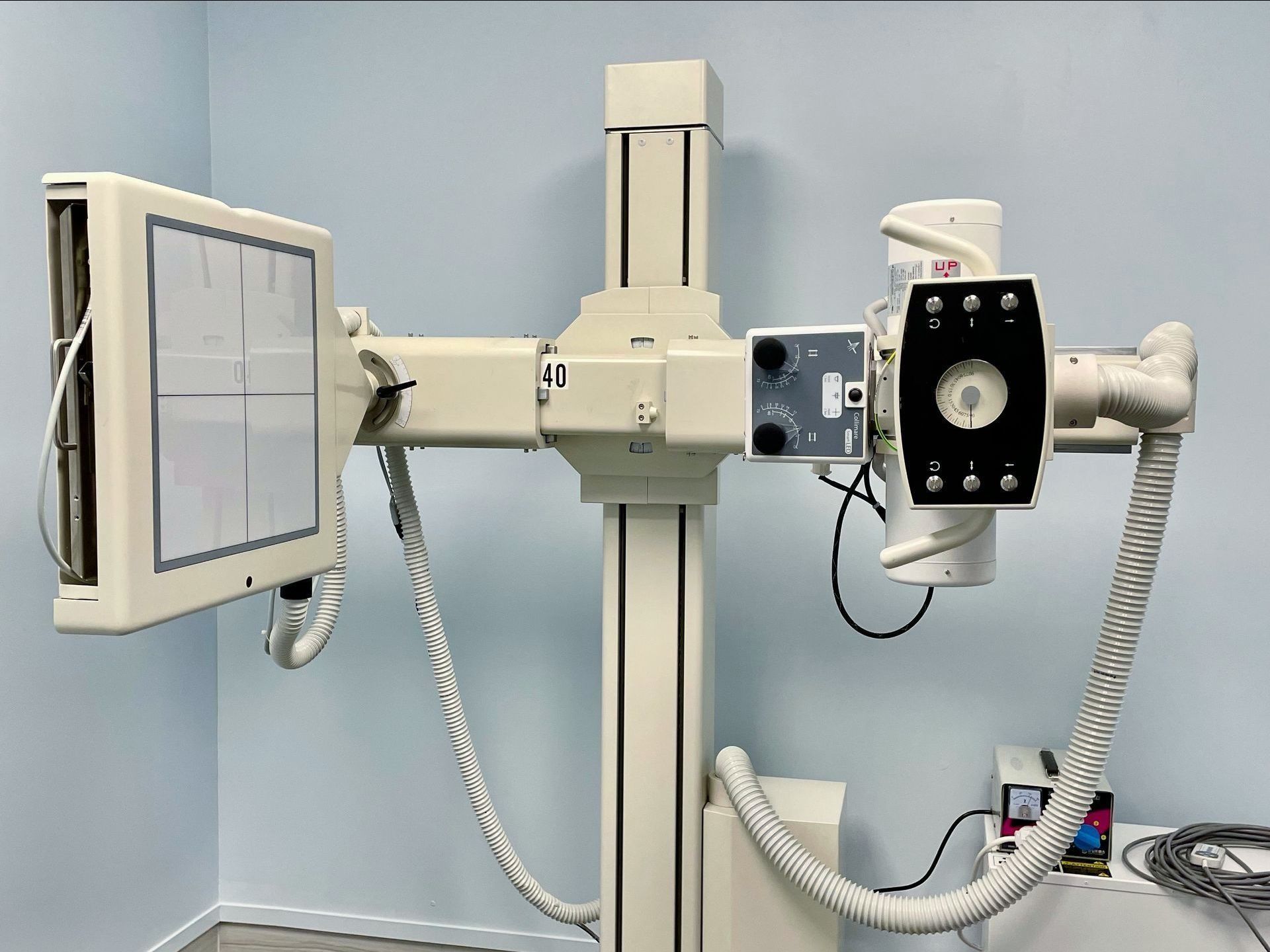 An x-ray machine is sitting in a room with a monitor attached to it.