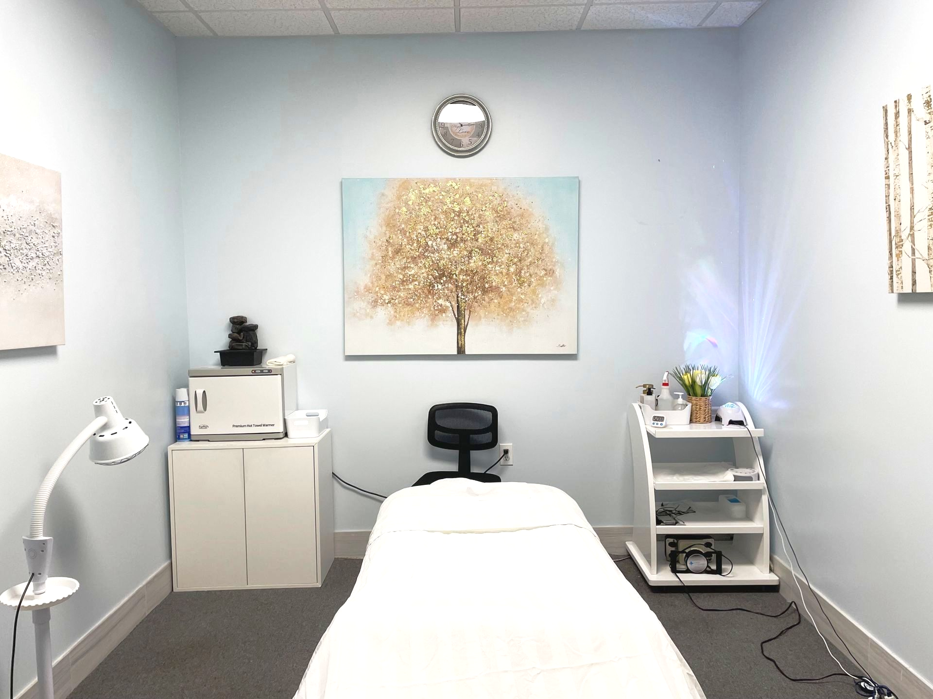 A massage table in a room with a painting of a tree on the wall