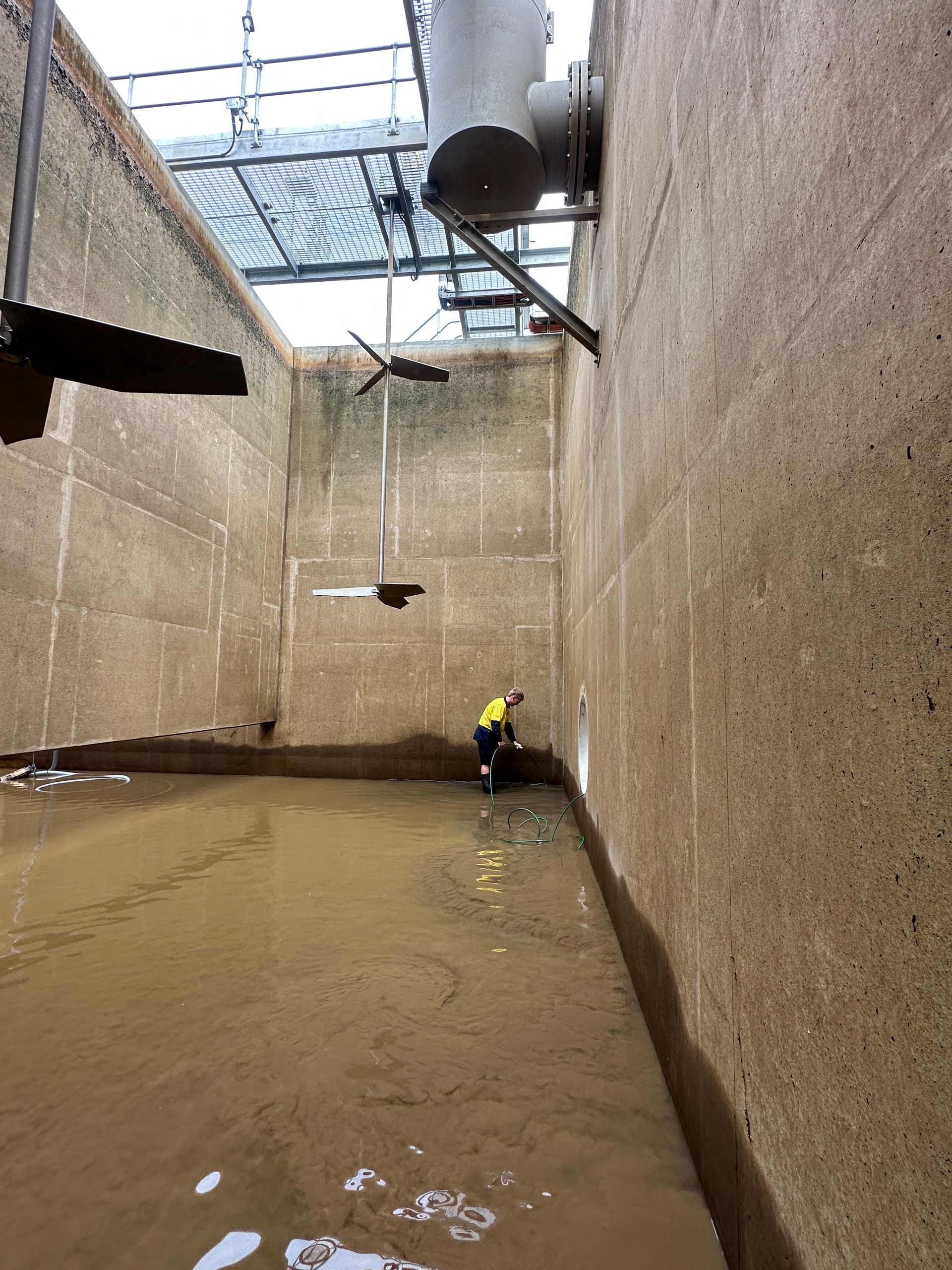 A Worker in a Water Tank With Mixers, Inspecting the Tank — Northern Plumbing In North Ward, QLD