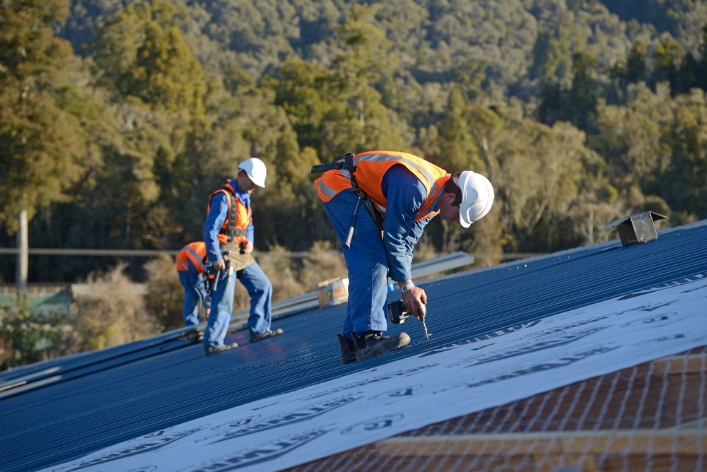 Three Men Are Standing On Top Of A Metal Roof — Northern Plumbing In Mount Louisa, QLD
