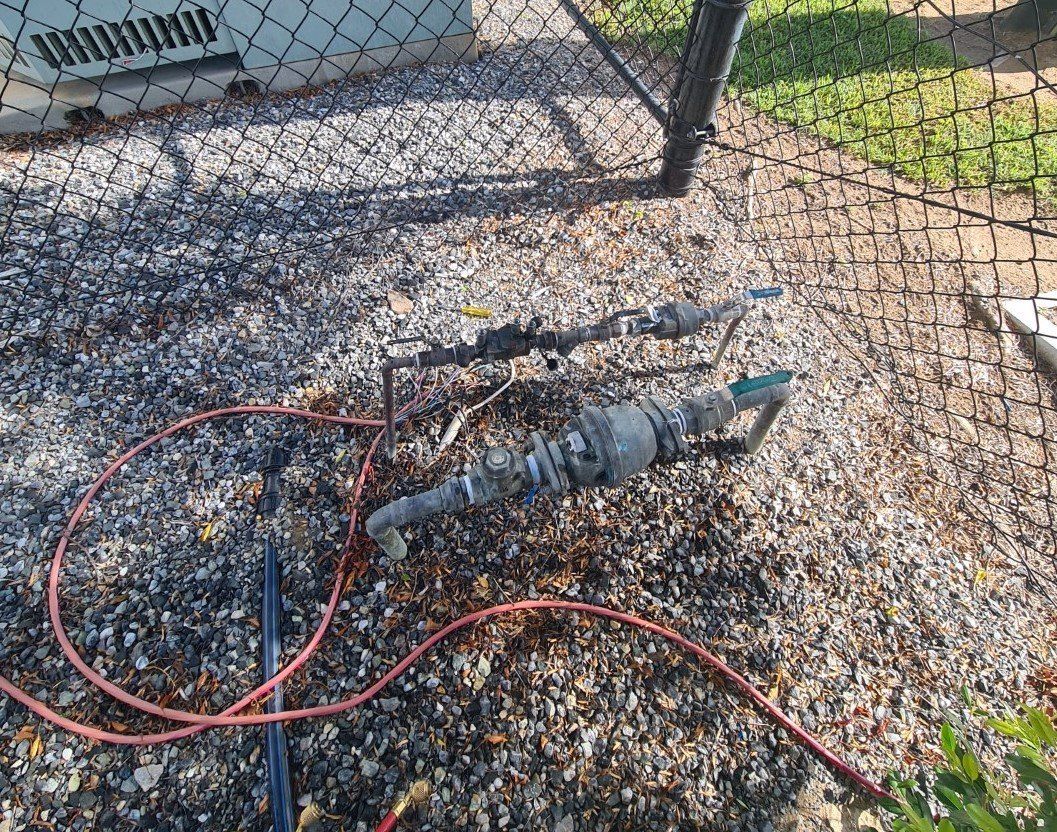 Pipes and Tubing on a Gravel Surface Next to a Chain-link Fence — Northern Plumbing In Hermit Park, QLD