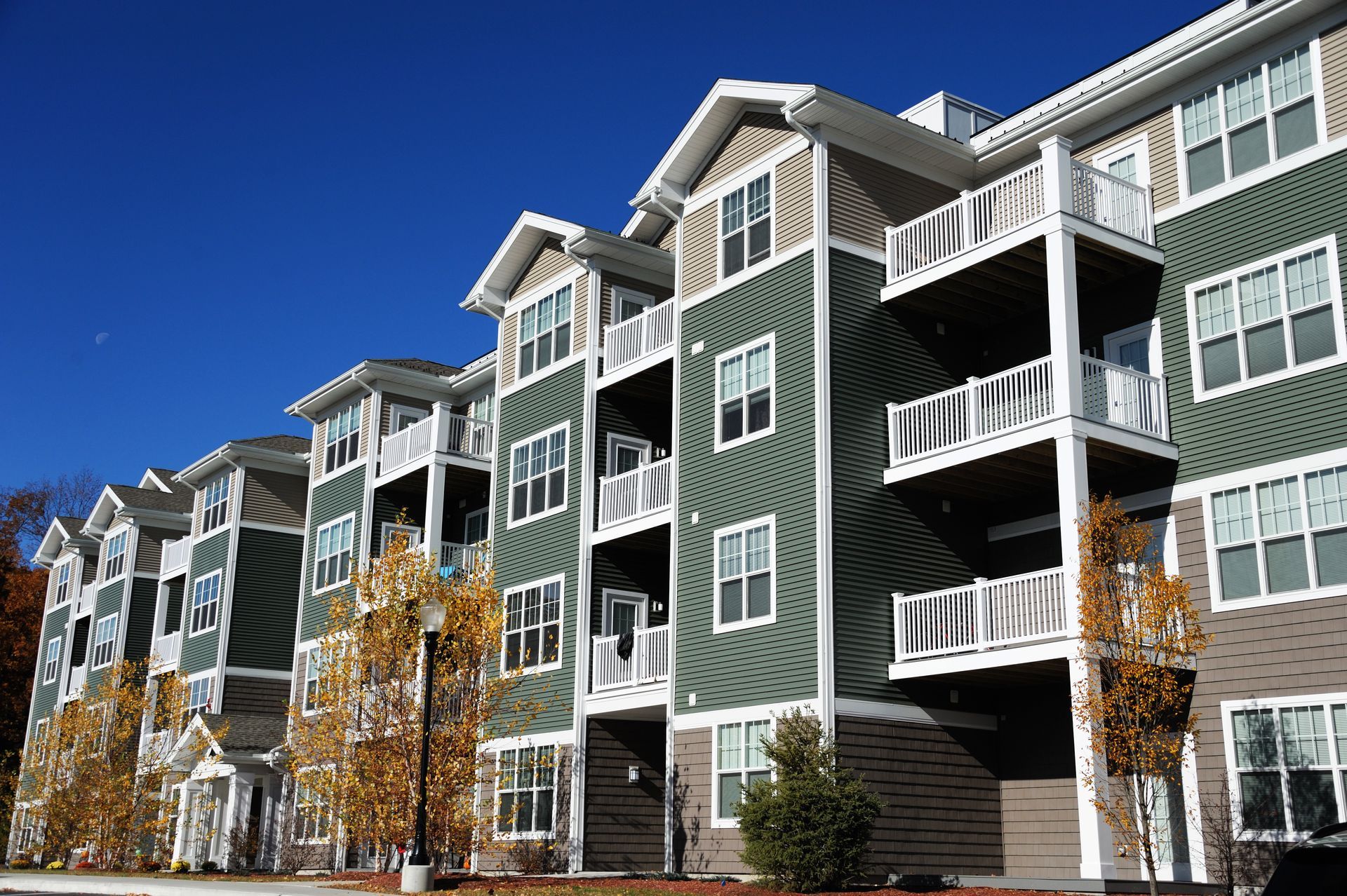 A large apartment building with green siding and white balconies