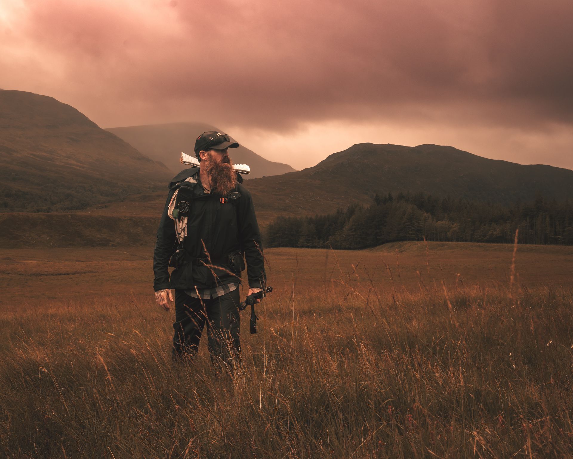 A man standing in a field with mountains in the background