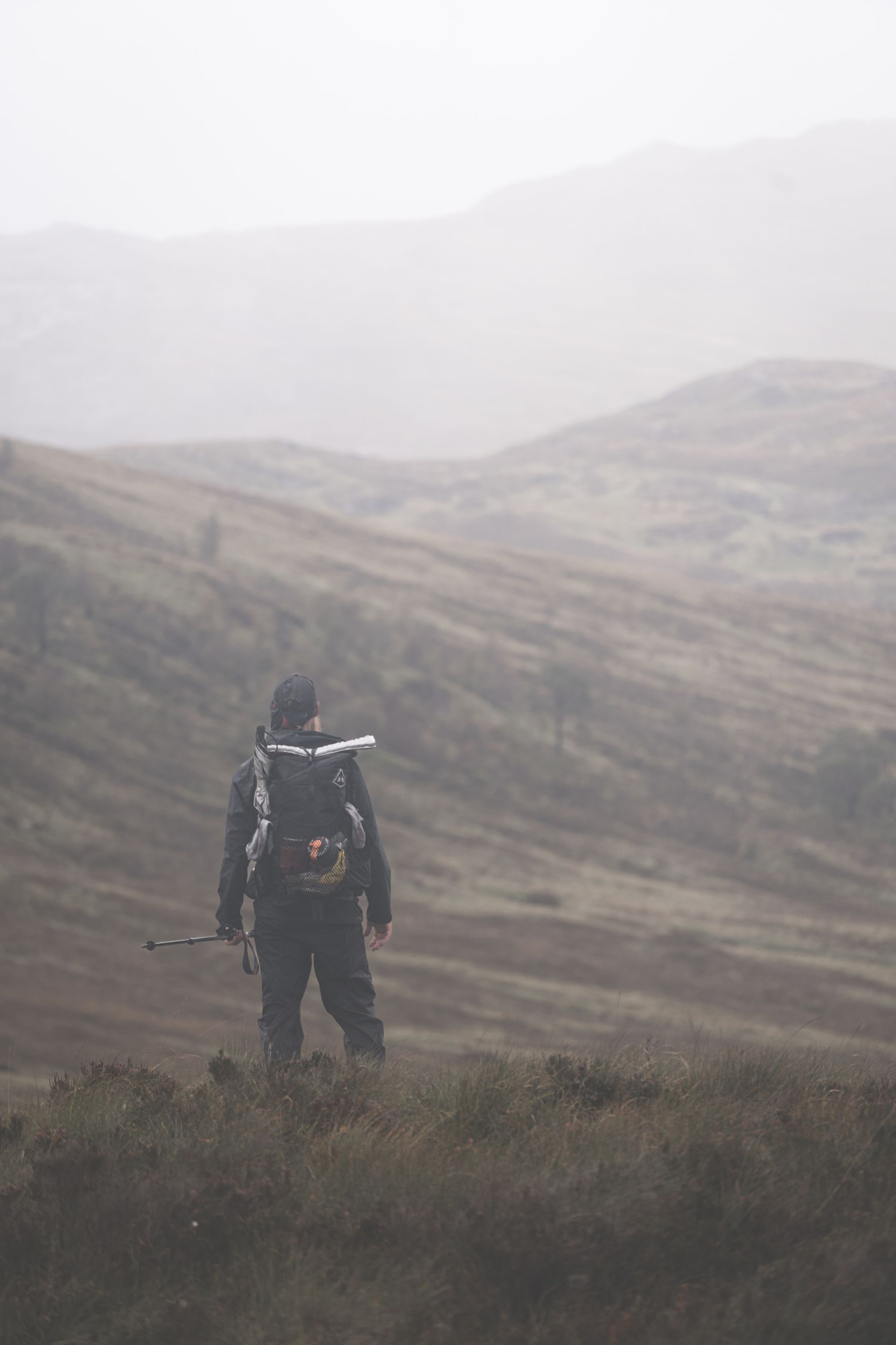 A person with a backpack is walking through a field.