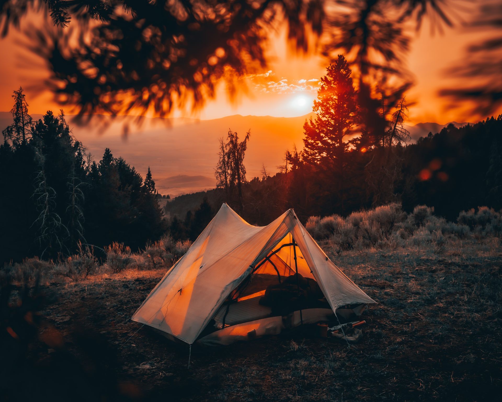 A tent is sitting in the middle of a field at sunset.