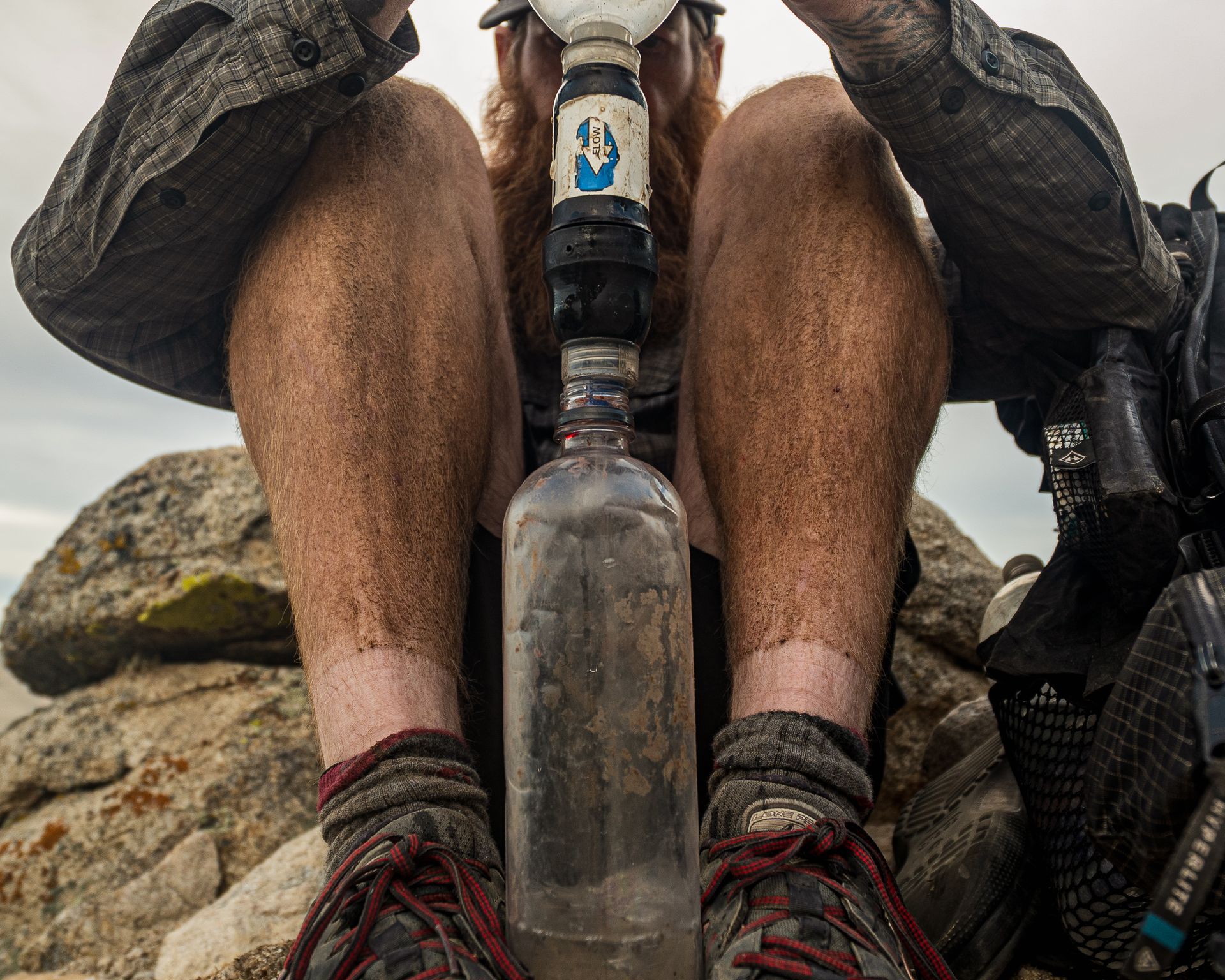 A man is sitting on a rock holding a bottle of water.