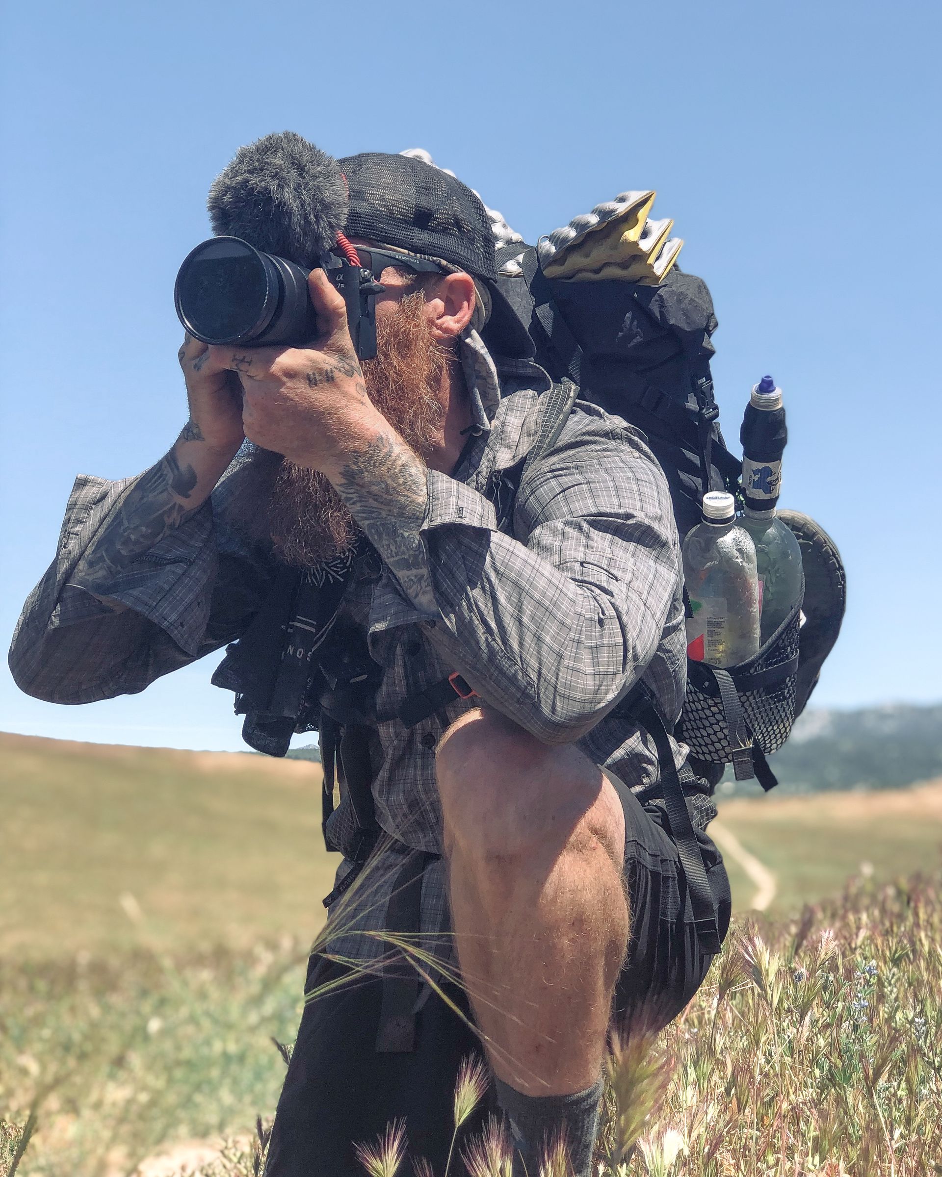 A man with a backpack is taking a picture with a camera