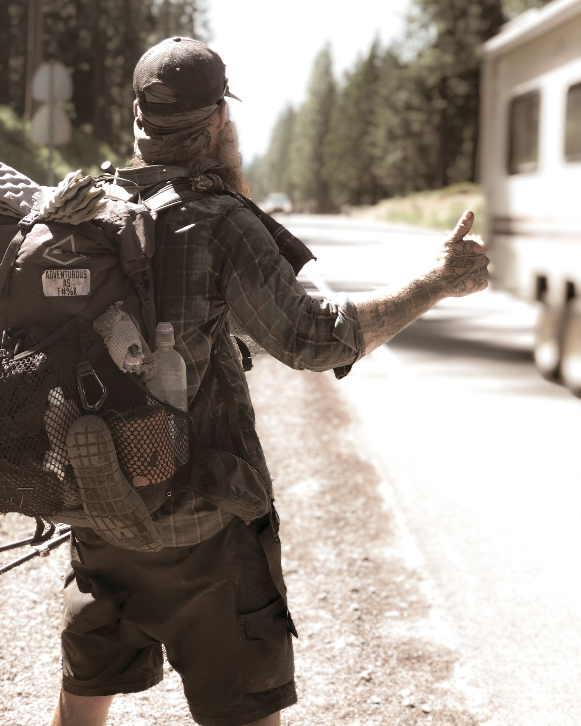 A man with a backpack giving a thumbs up