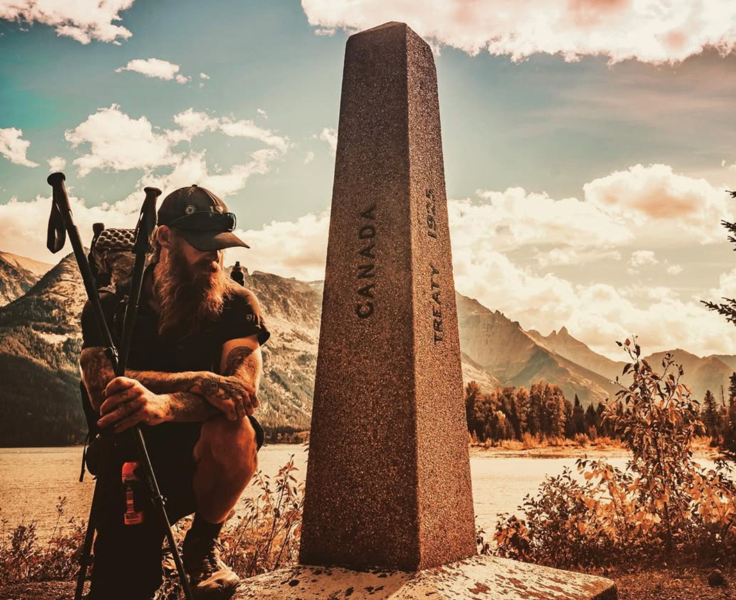 A man kneeling next to a stone pillar that says canada