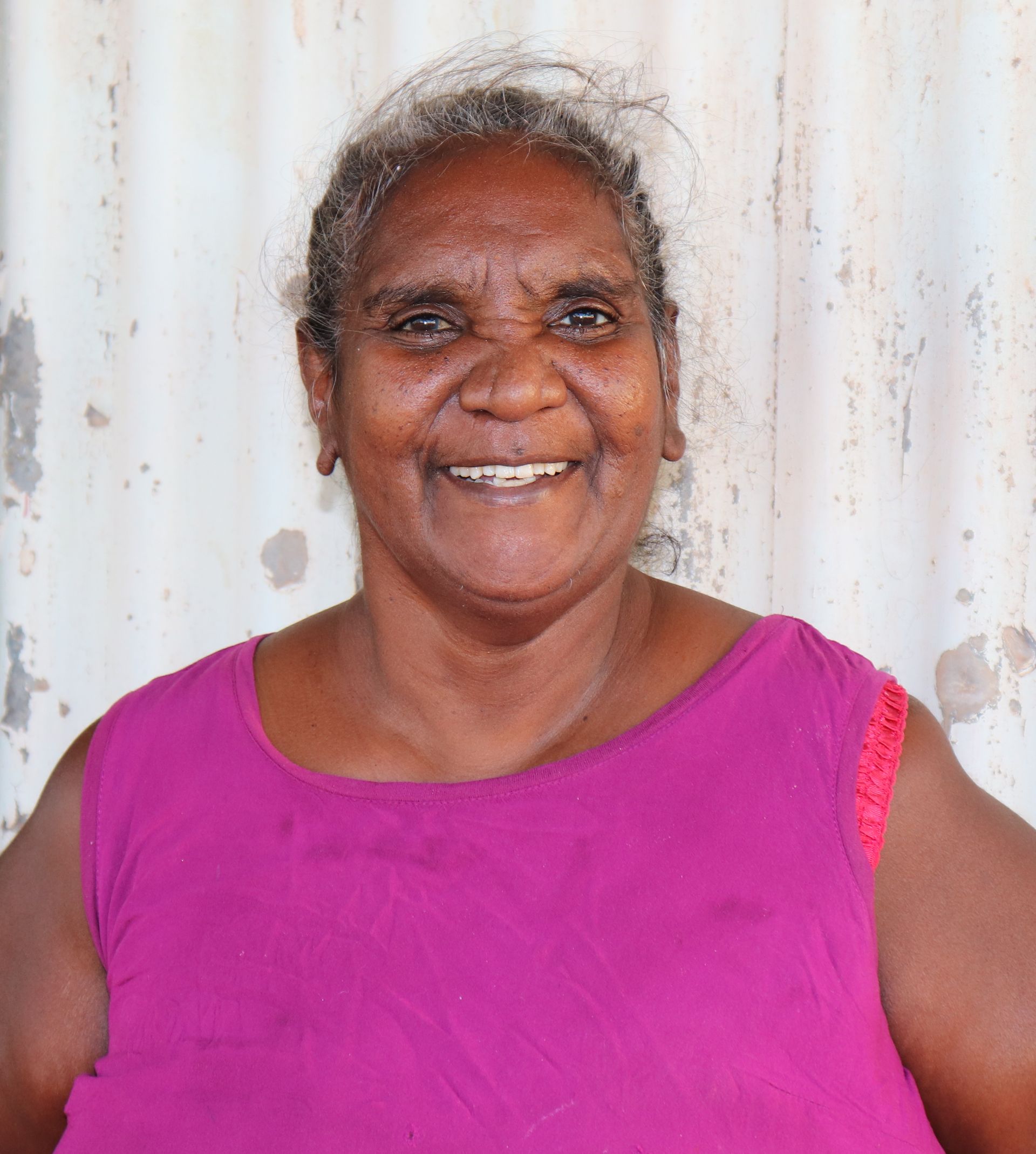 A woman in a purple tank top is smiling for the camera.