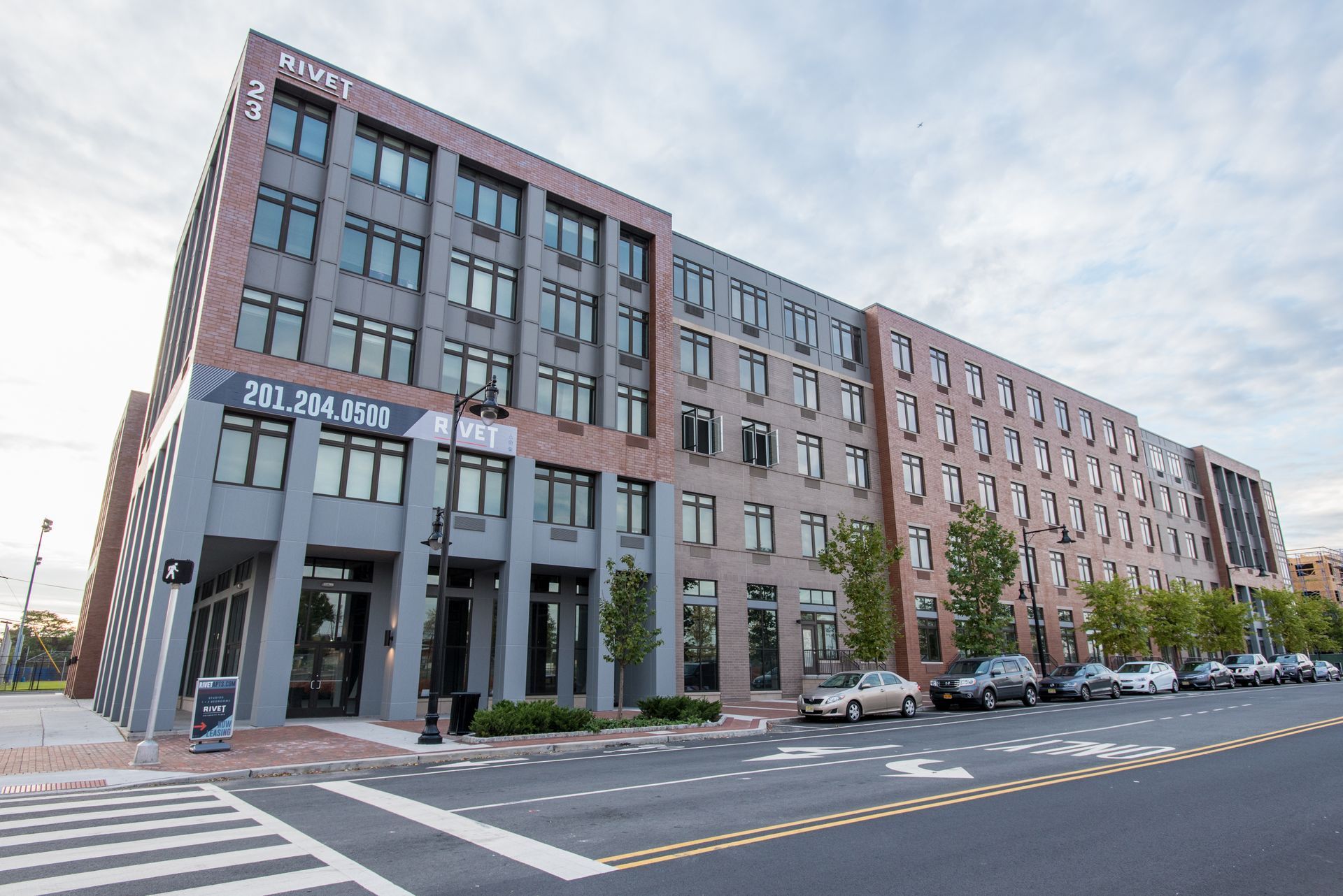 A large building with a lot of windows is sitting on the corner of a street.