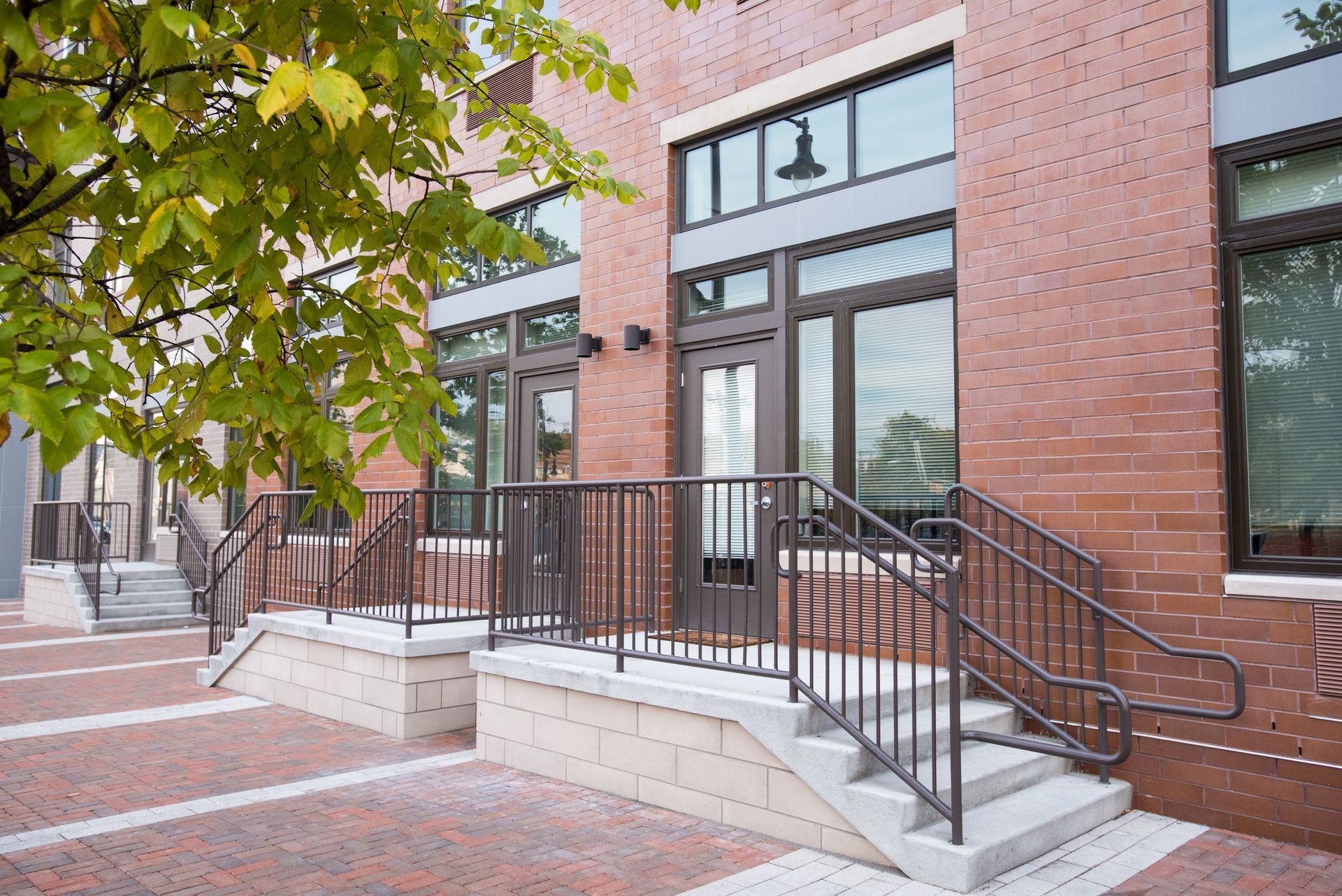 A brick building with stairs and a tree in front of it