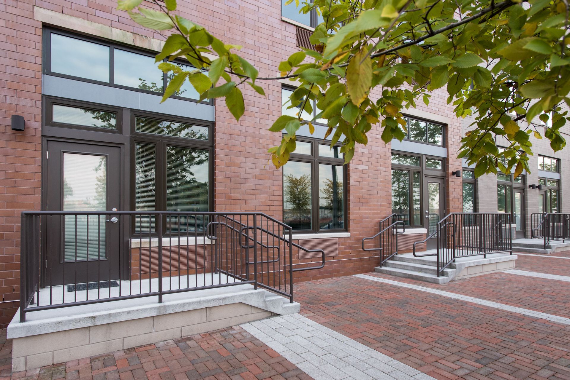 A brick building with stairs and a tree in front of it