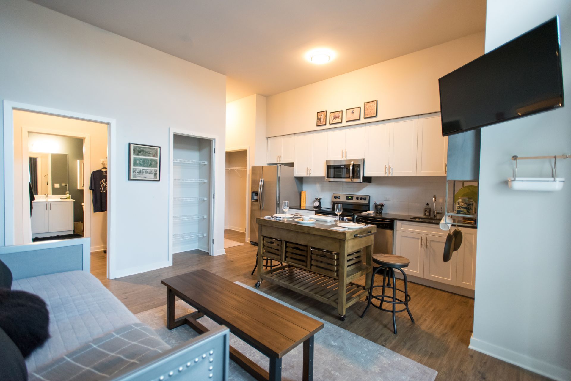 A living room with a couch , table , television and kitchen.