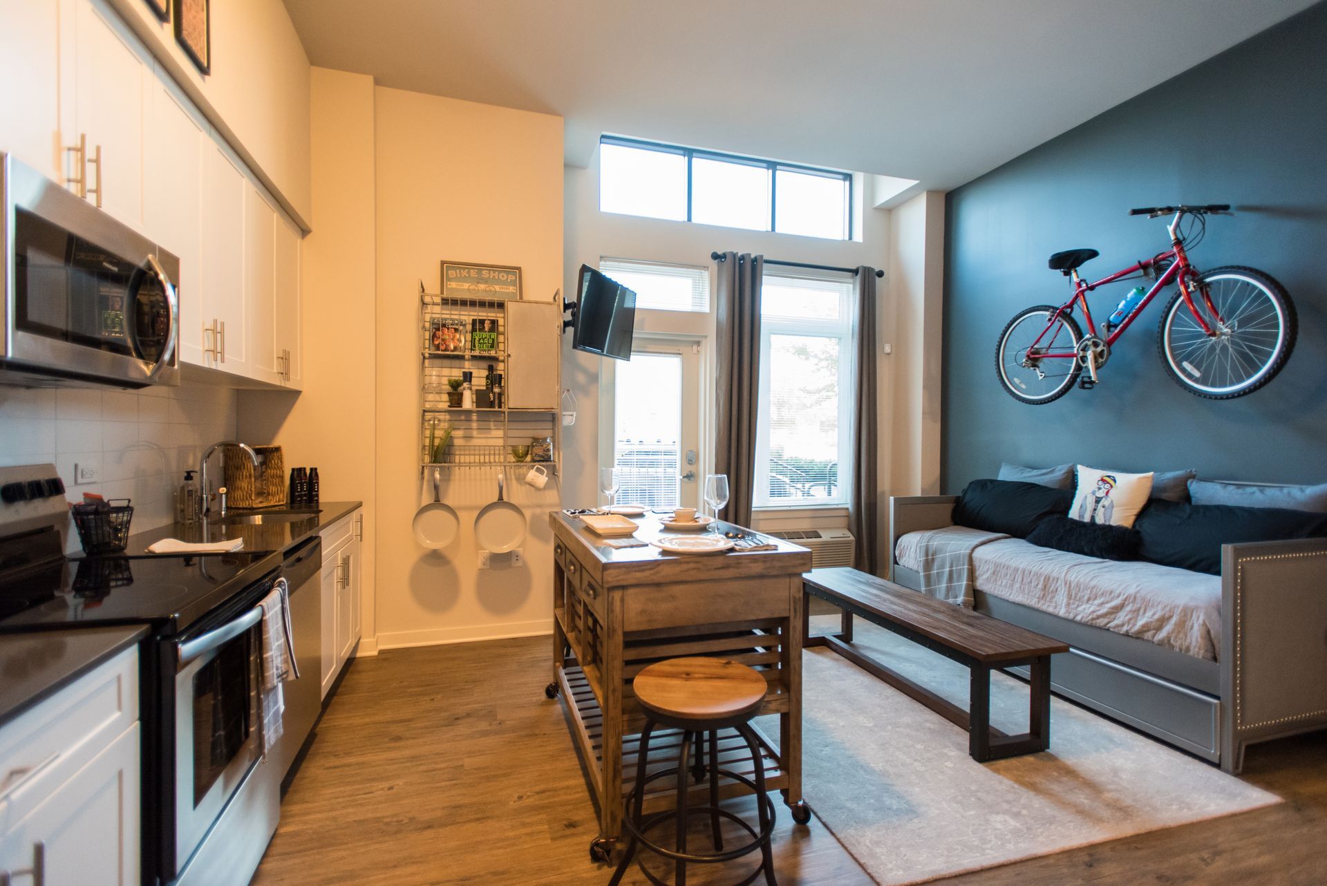 A kitchen and living room with a bicycle hanging on the wall.