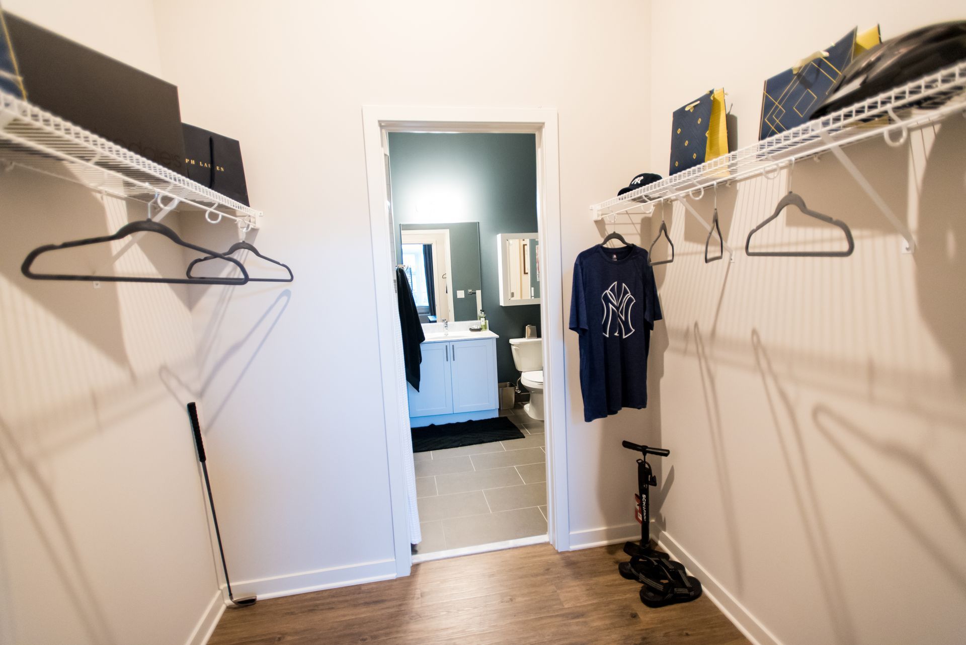 A walk in closet with a t-shirt hanging on the wall.