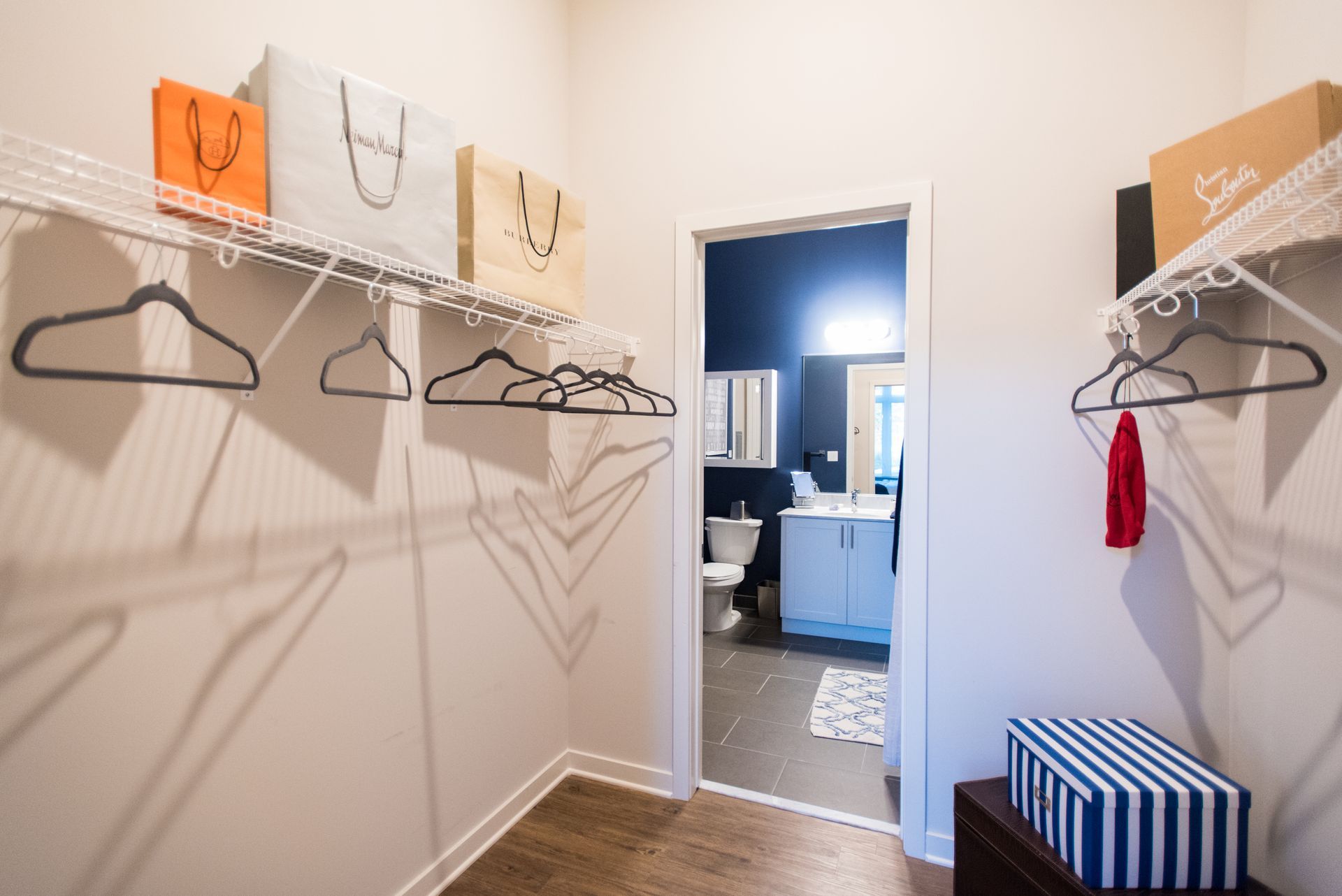 A walk in closet with clothes hanging on racks and a bathroom in the background.
