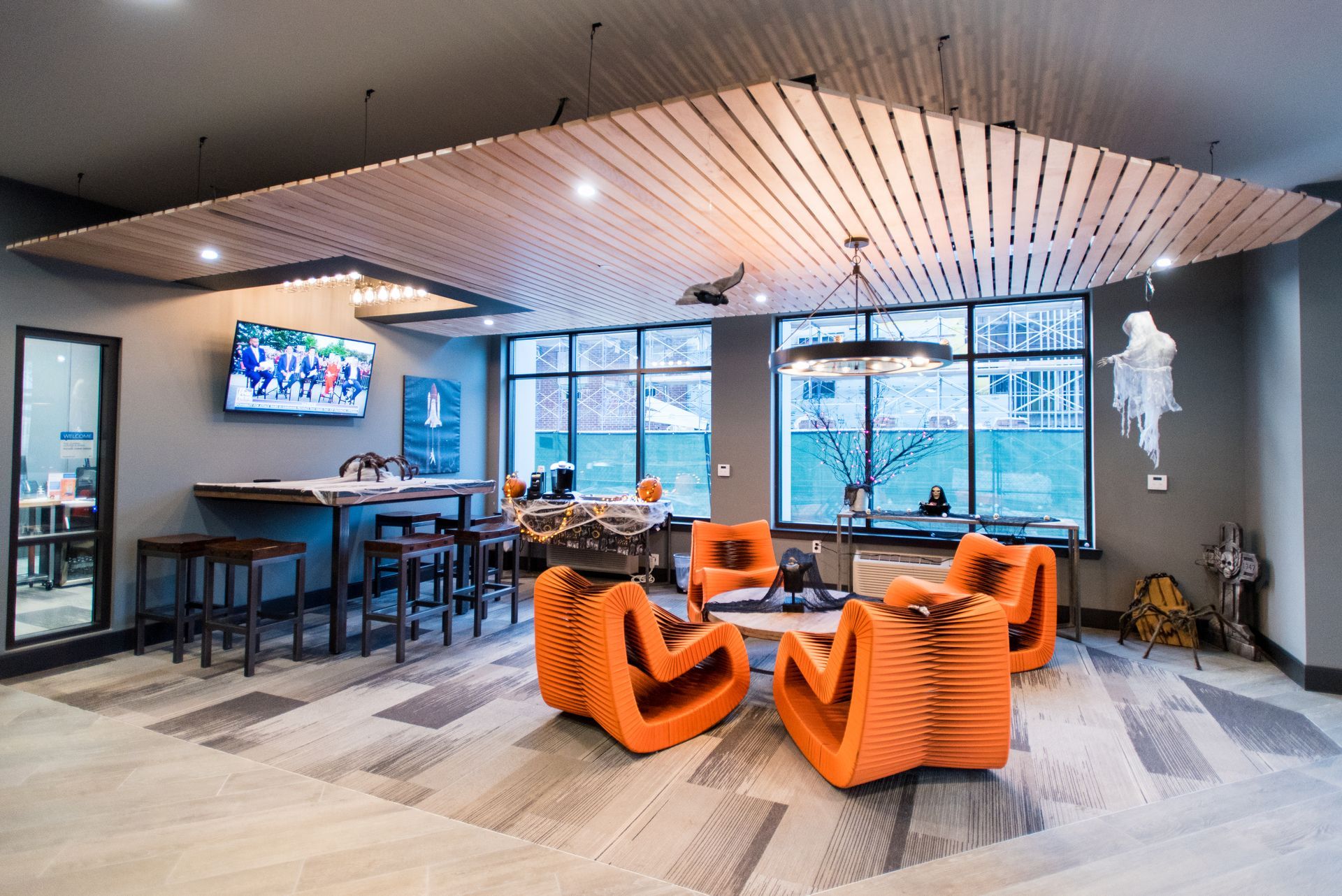 A living room with orange chairs and a television on the wall.