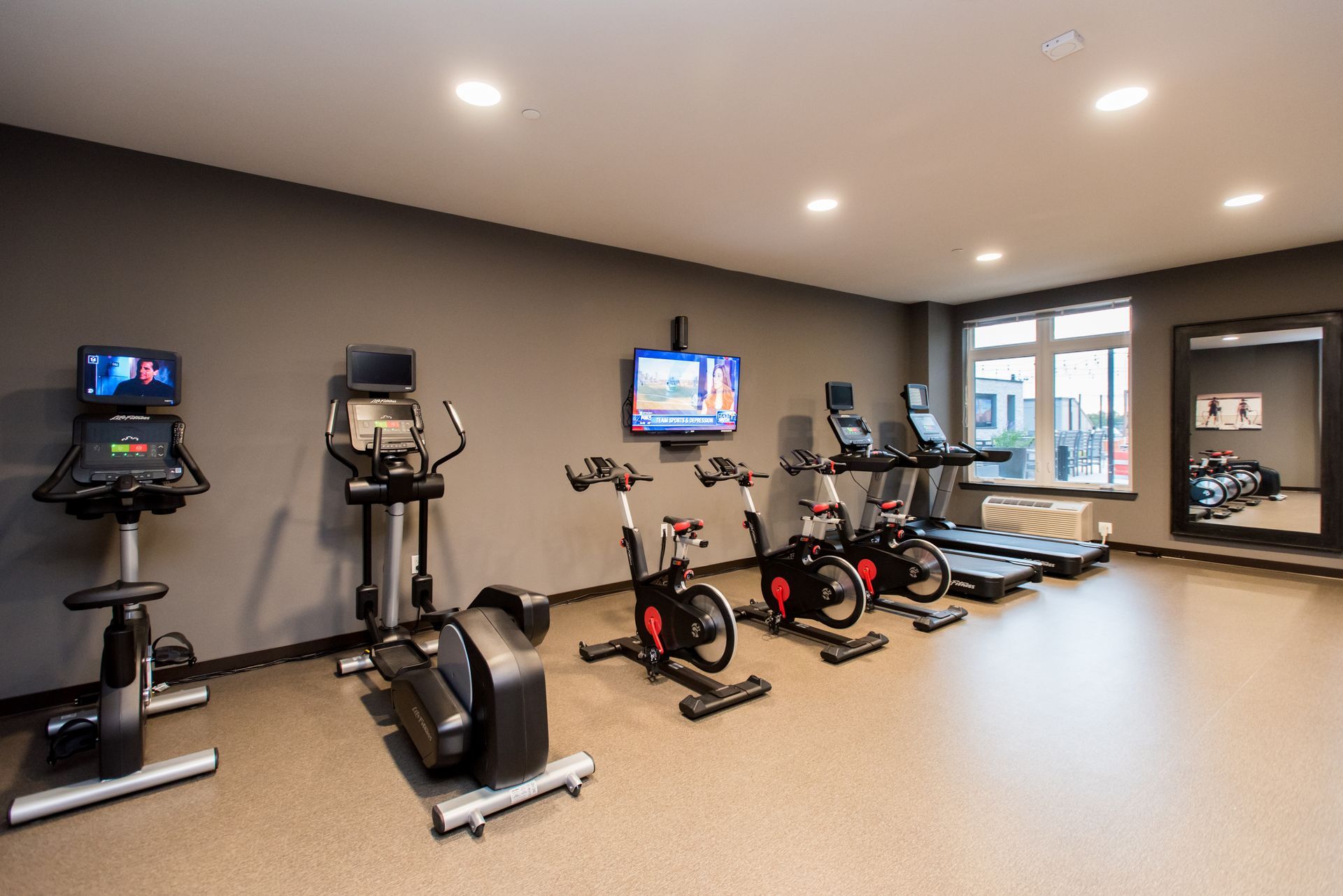 A gym with a lot of exercise equipment and a large mirror.