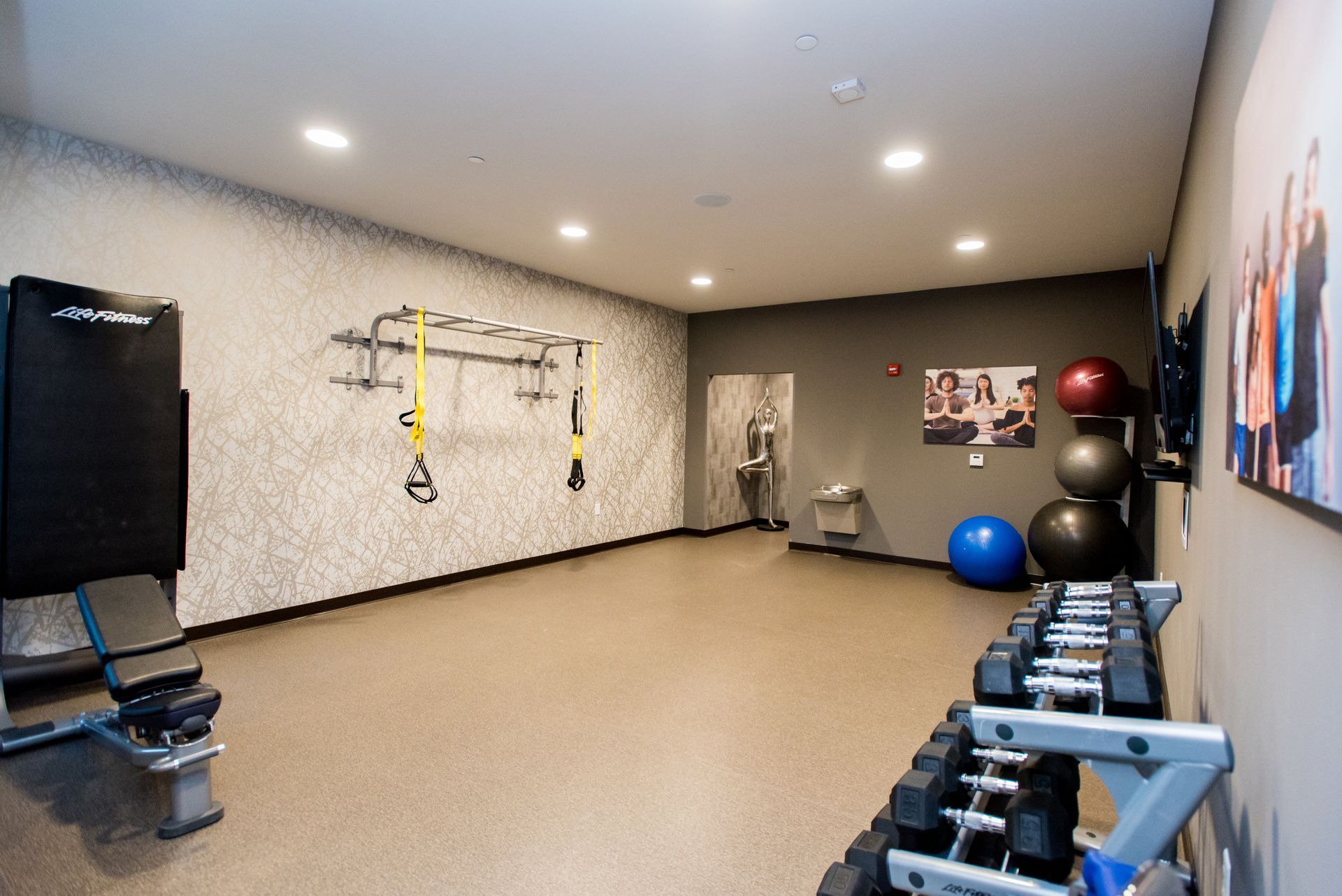 A gym with a lot of dumbbells and balls on the floor