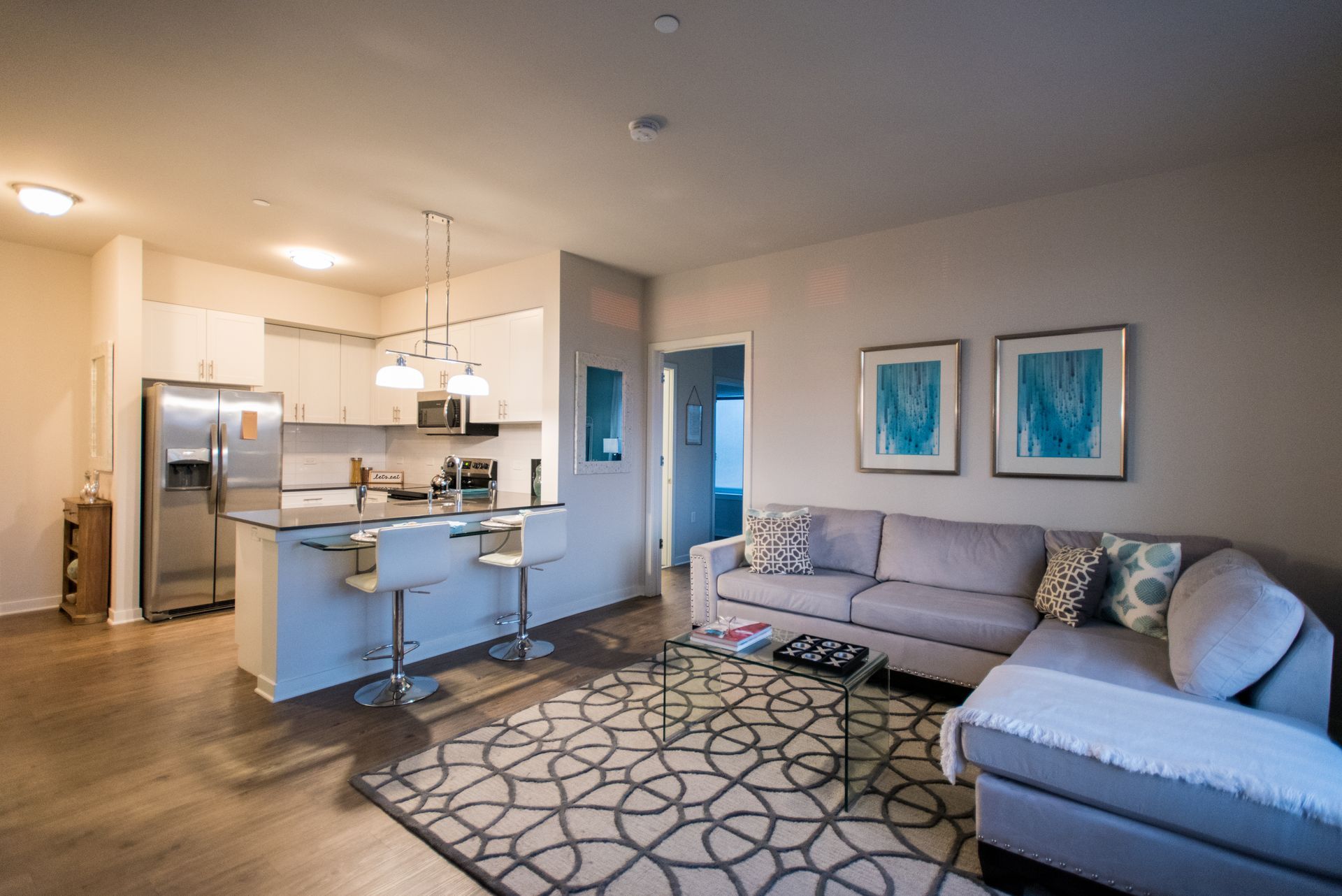 A living room with a couch , coffee table , rug and kitchen.