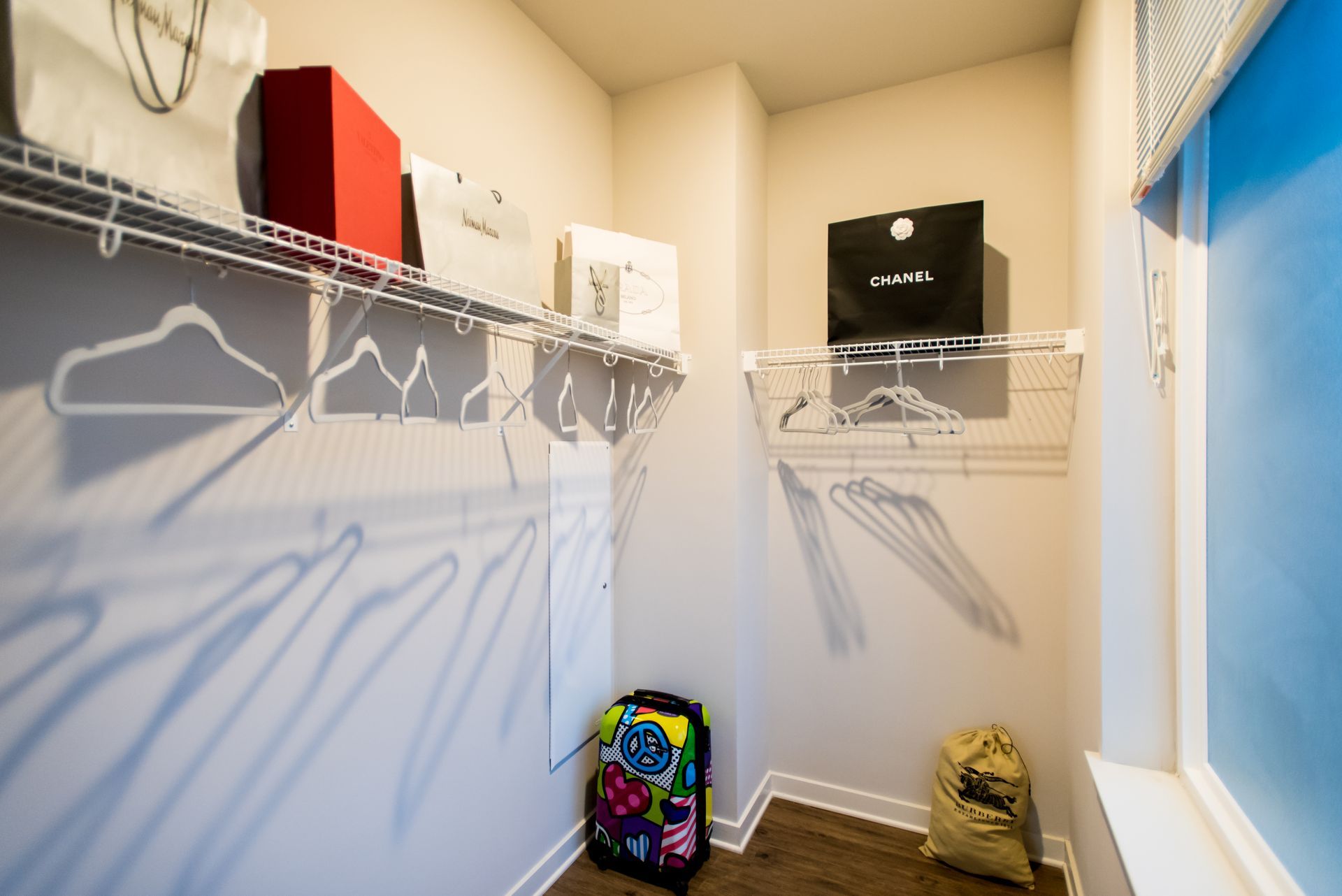 A walk in closet with a suitcase and a television on the wall.