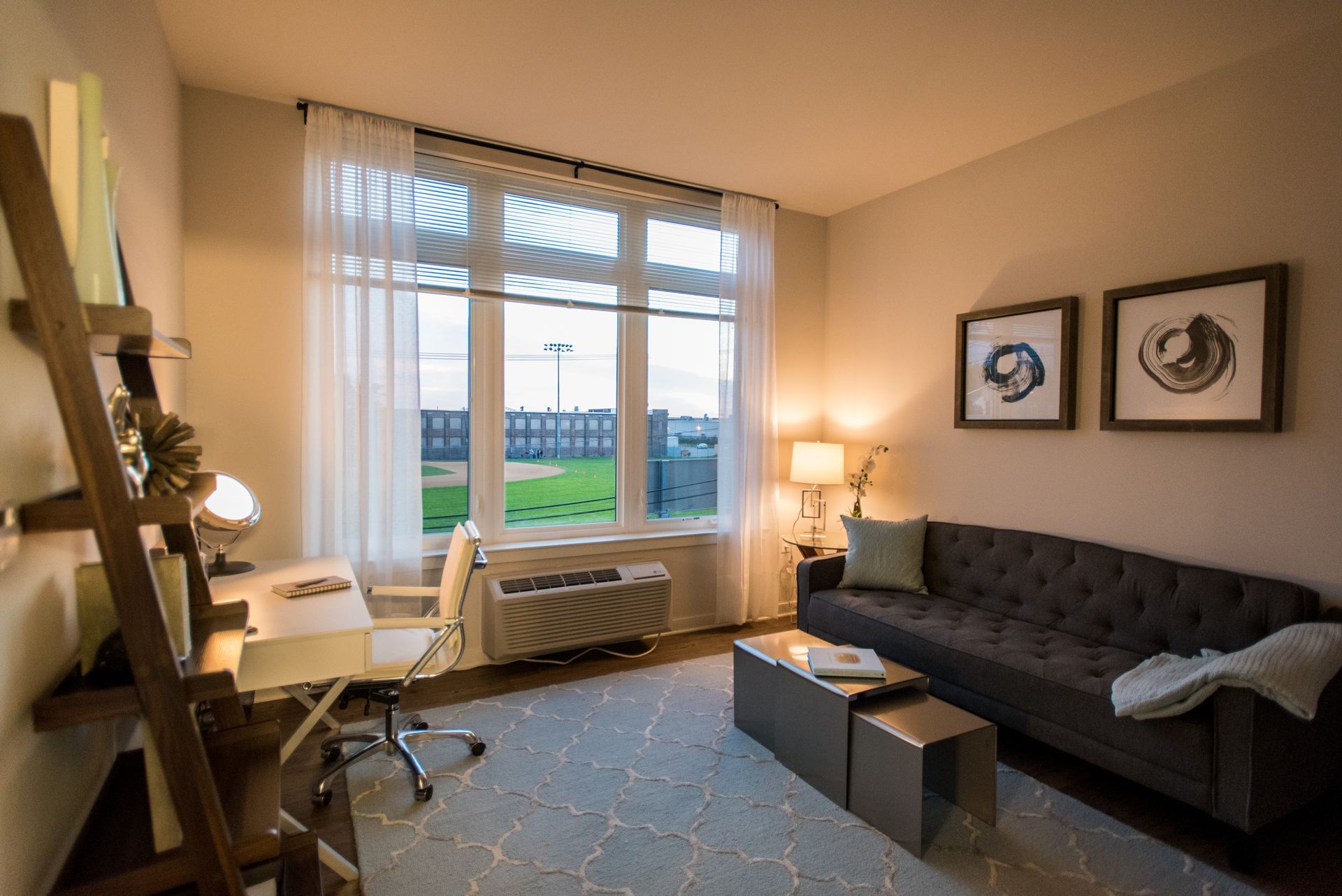 A living room with a couch , desk , chair and large window.